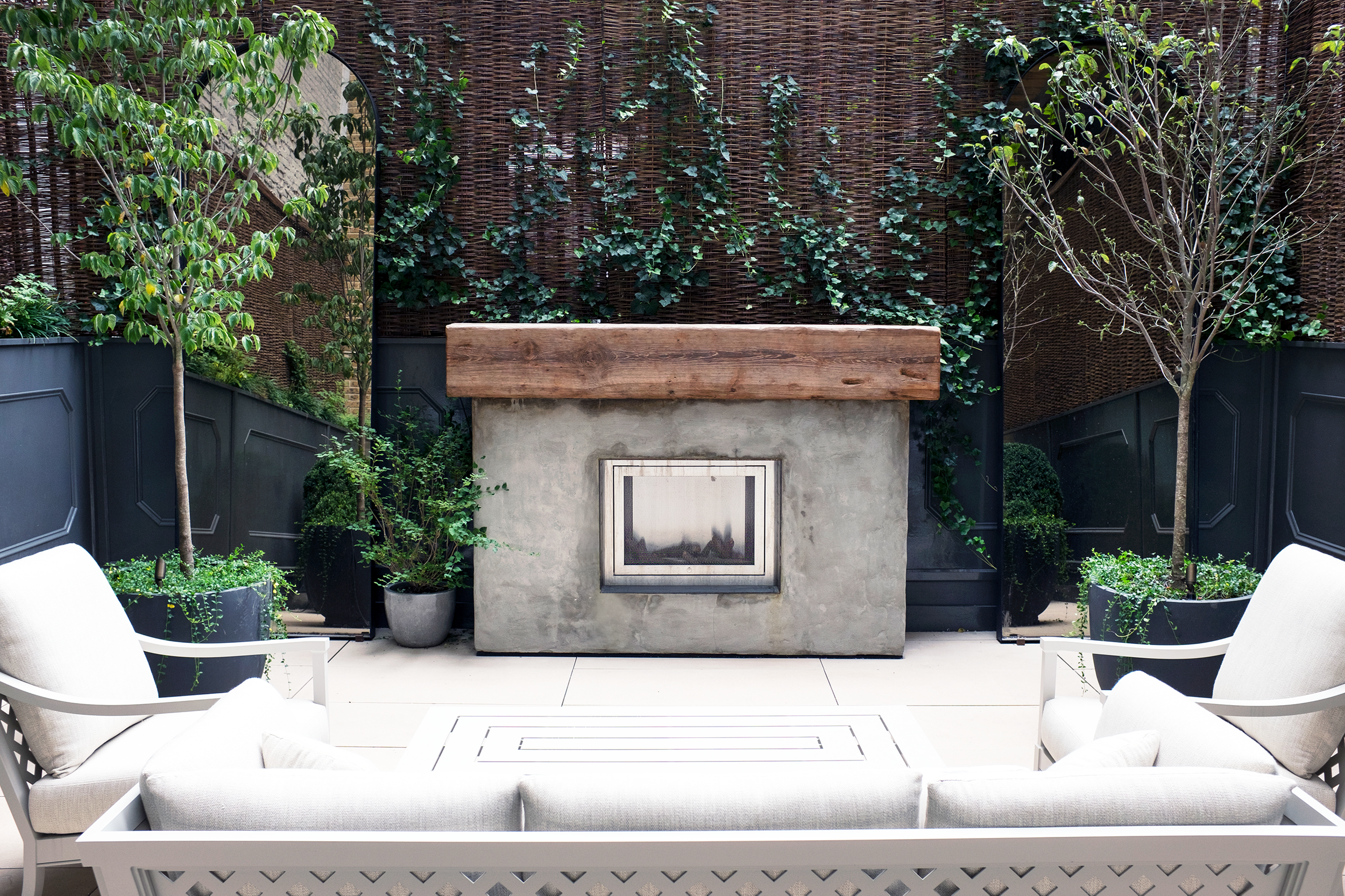 Union Square - Private Terrace : A photo showing the installation of a custom stucco fireplace with a reclaimed timber mantel and a custom panel wall with detail moldings.