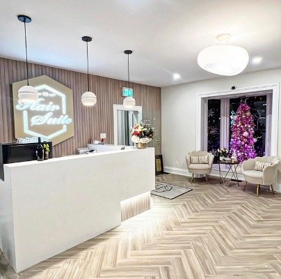 Reception area with a white desk, seating area with chairs, Christmas tree, and modern decor.