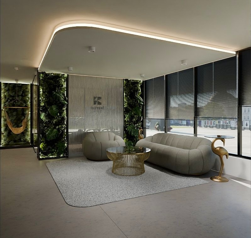 Modern lounge area with two curved sofas, a round glass coffee table with gold base, a gold flamingo side table, large windows with black shades, and greenery wall decor.