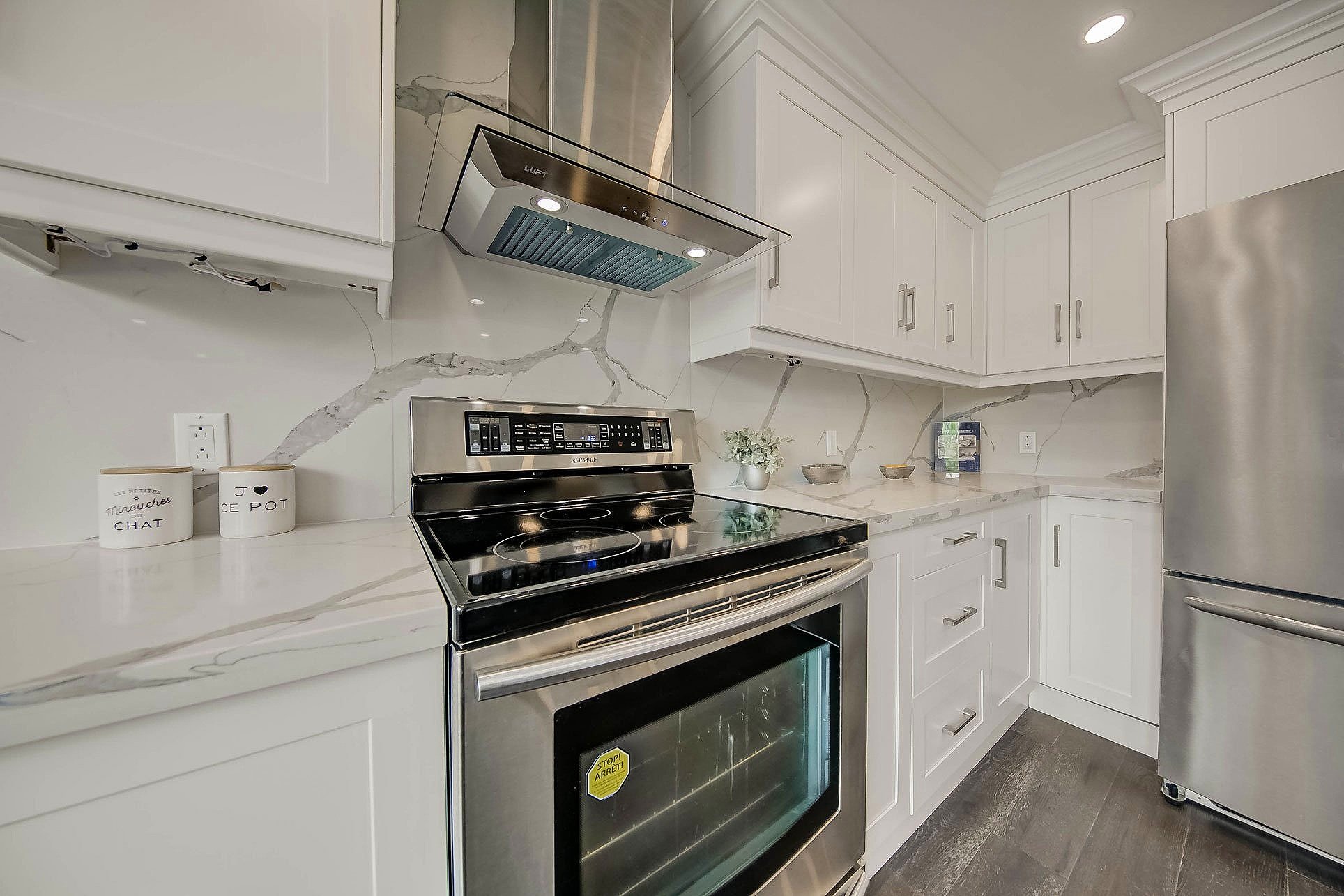 Kitchen with white cabinets, marble countertop, stainless steel appliances, and a marble backsplash.