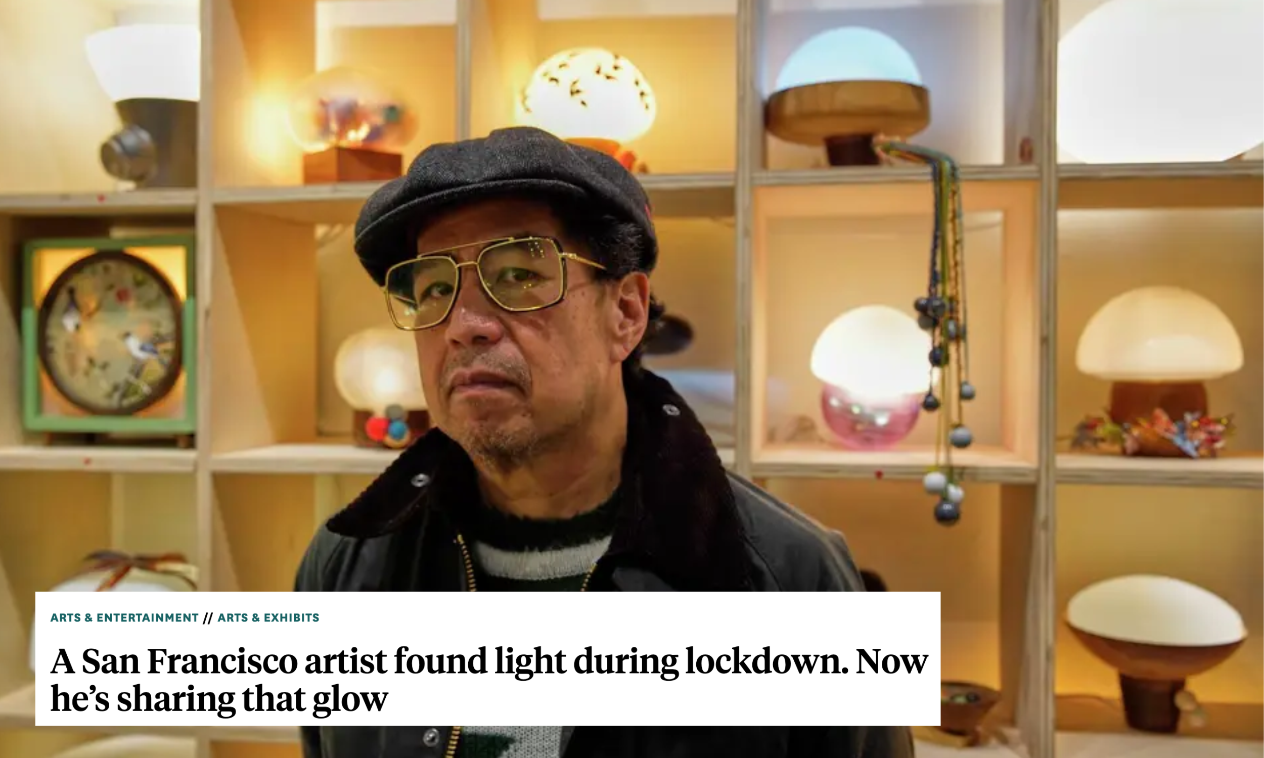 Poet-artist Truong Tran standing in front of a wall of lamps he made for his exhibition "100 Nights of the Pandemic/100 Days of Yearning."