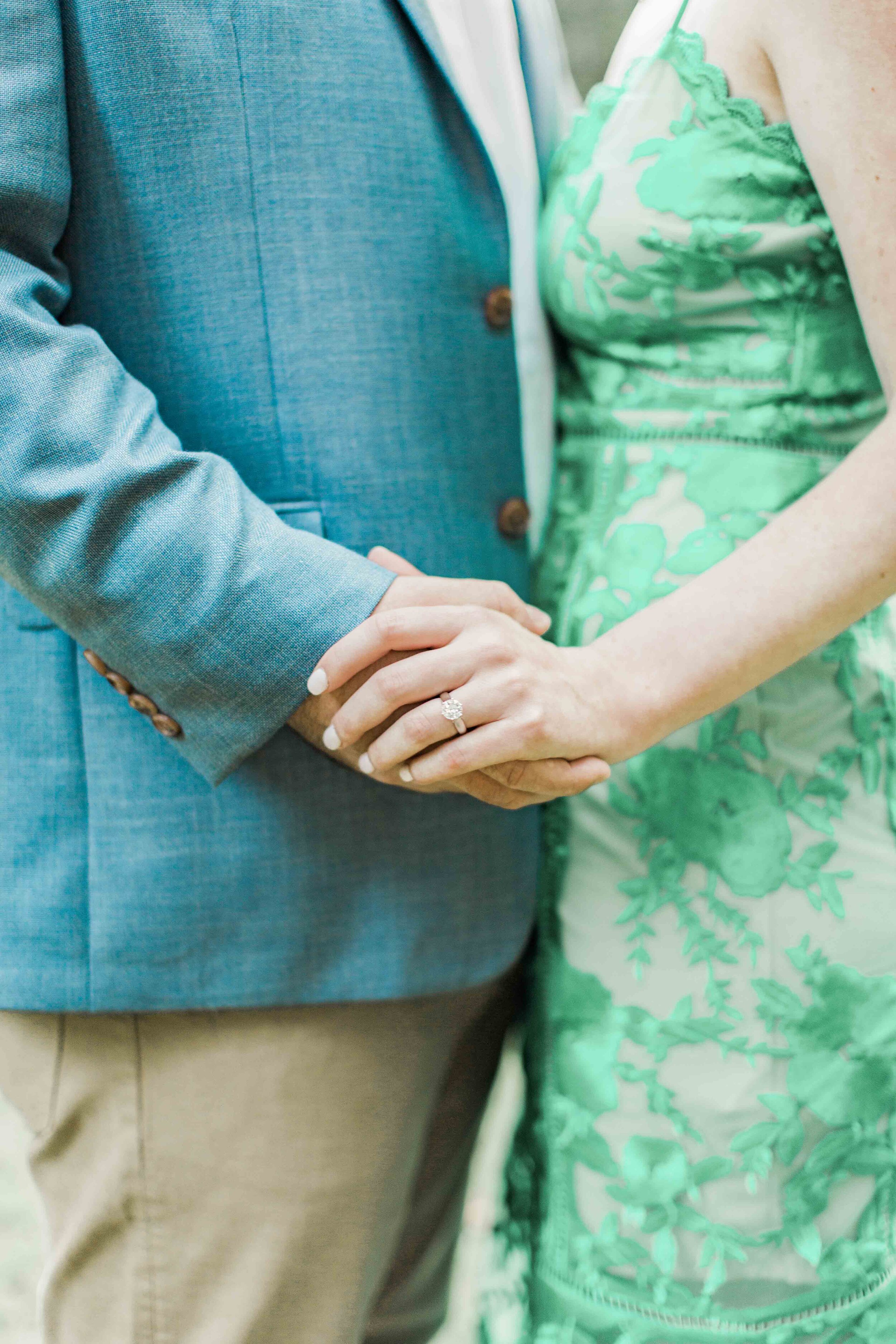 Newly engaged couple hold hands with a gorgeous solitaire diamond ring