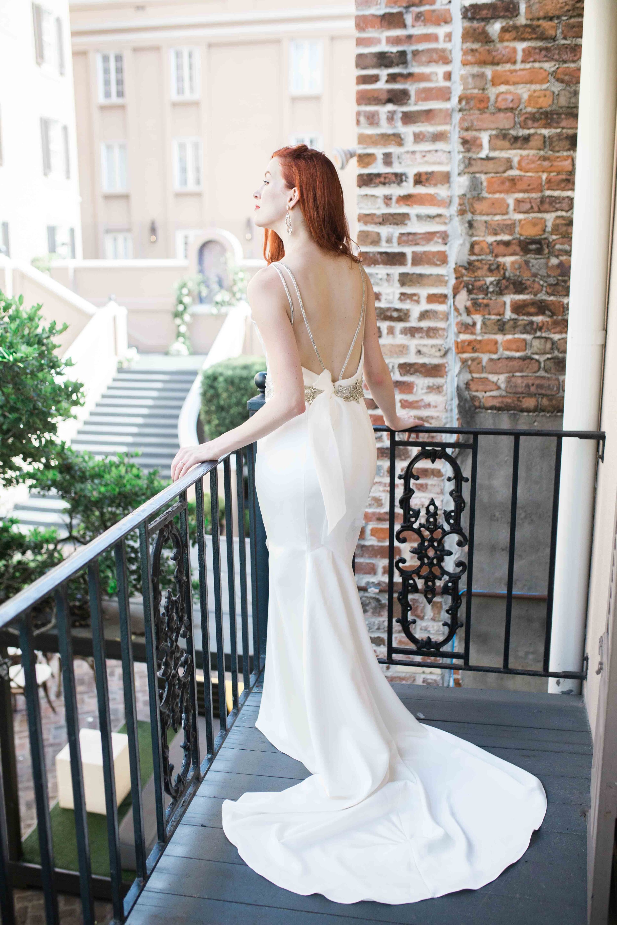 Gorgeous red hair bride in wedding gown starring off the balcony