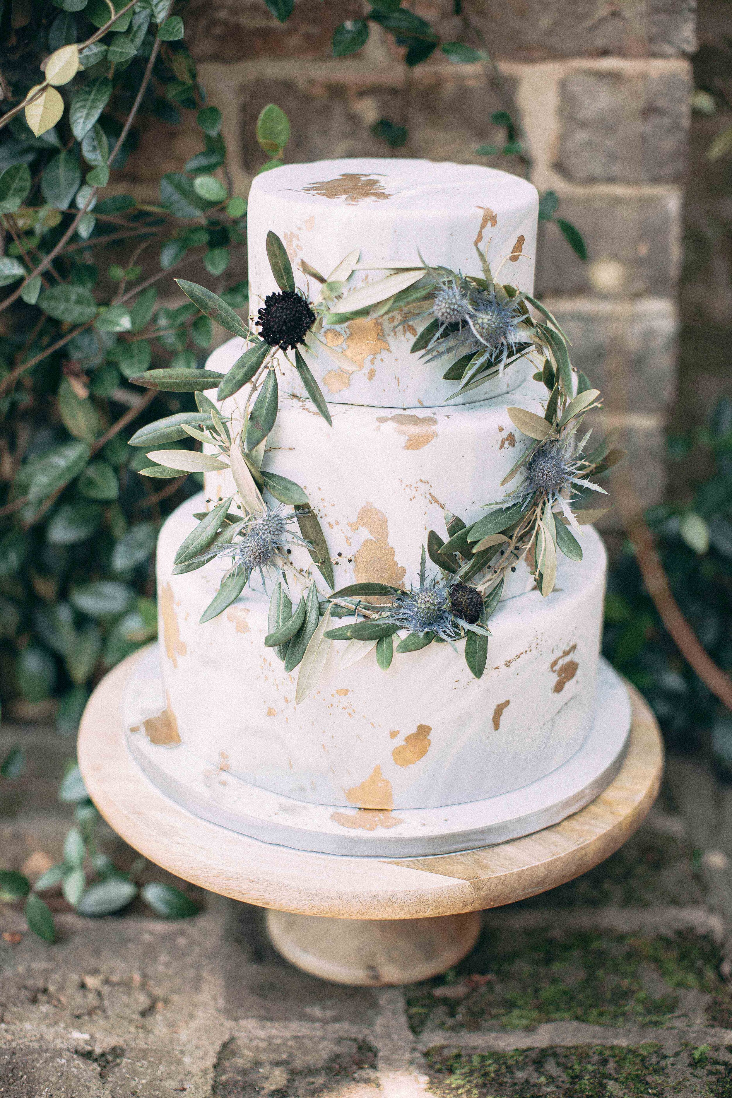 Vintage cake with watercolor and gold leave design adorned with natural greenery