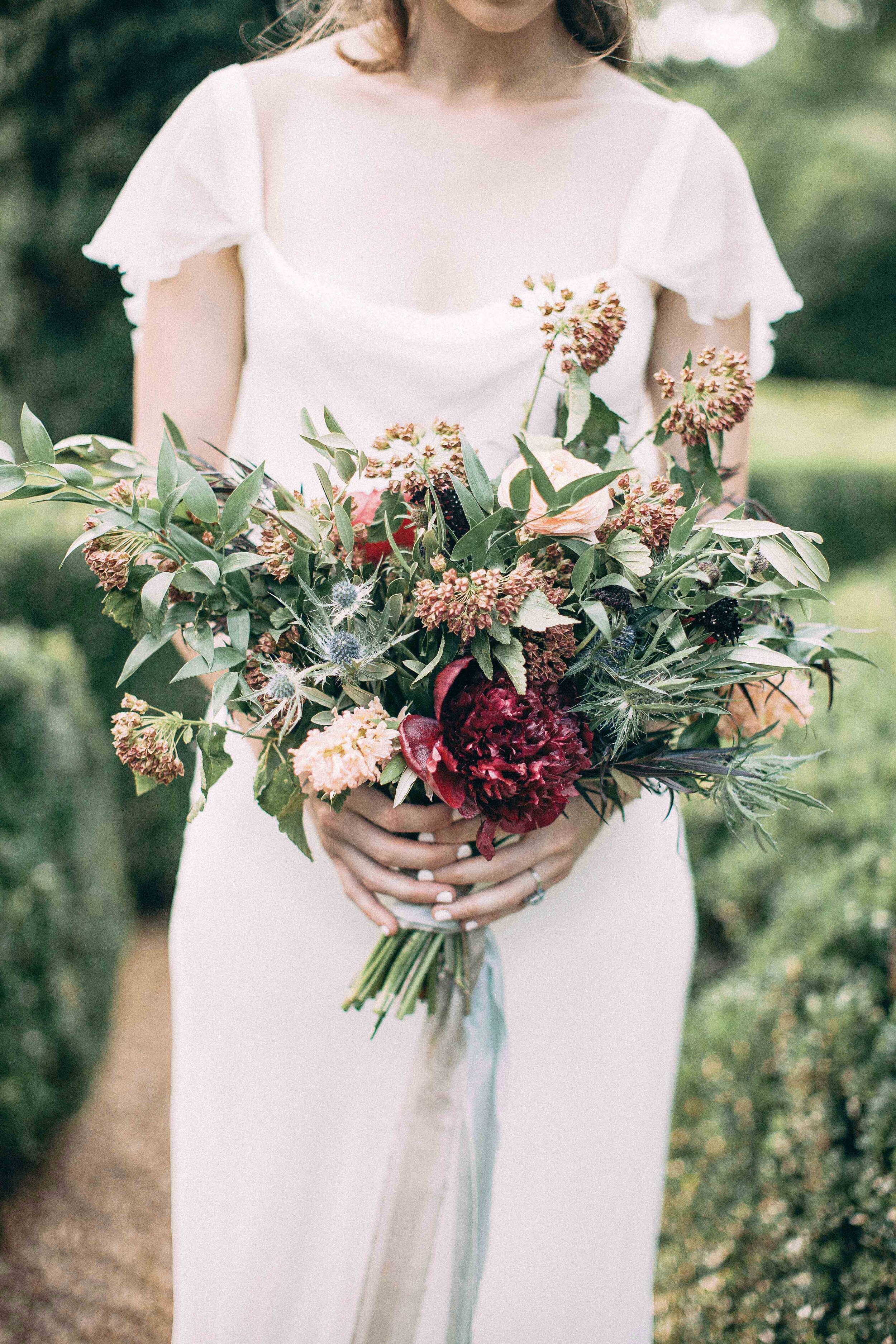 Wild asymmetrical bouquet with red peonies and greenery