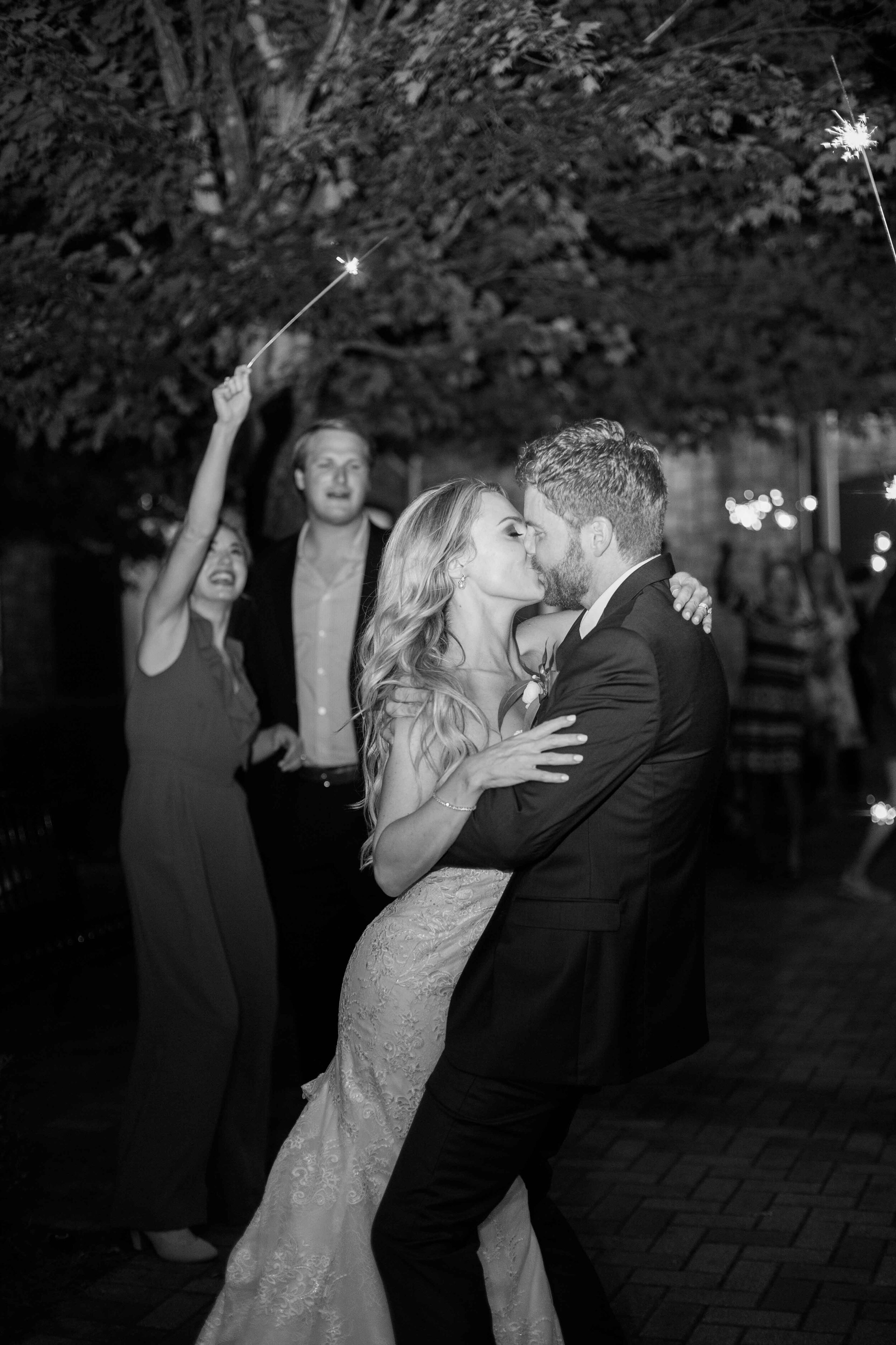 Black and white bride and groom sparkler exit kiss