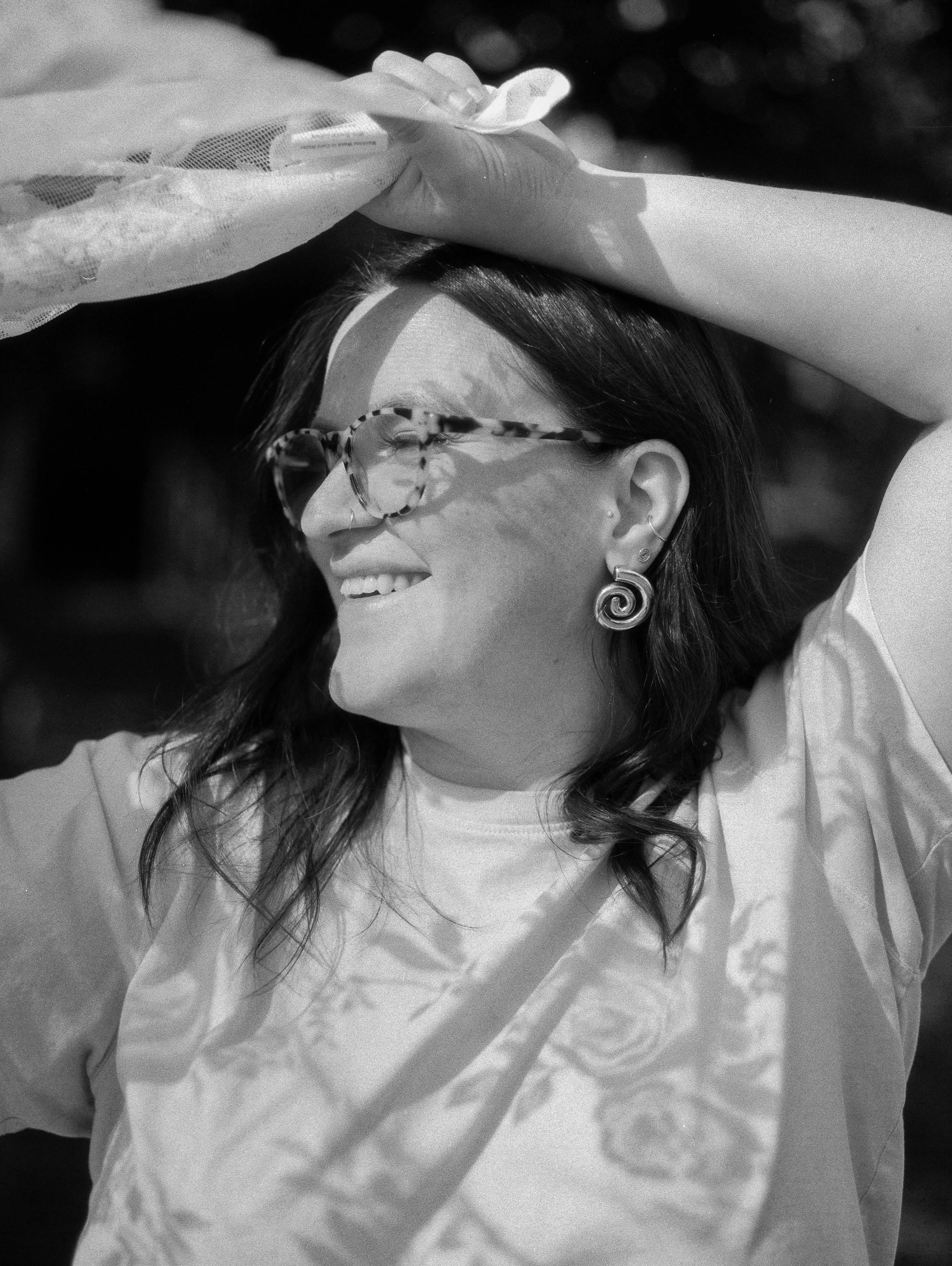 grainy film portrait of woman in lace patterns with spiral earrings and tortishell glasses