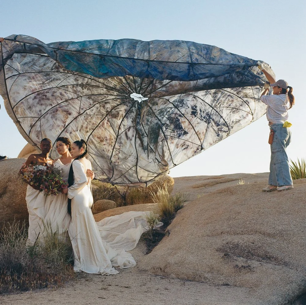 artists hold painted vintage parachute behind group of models