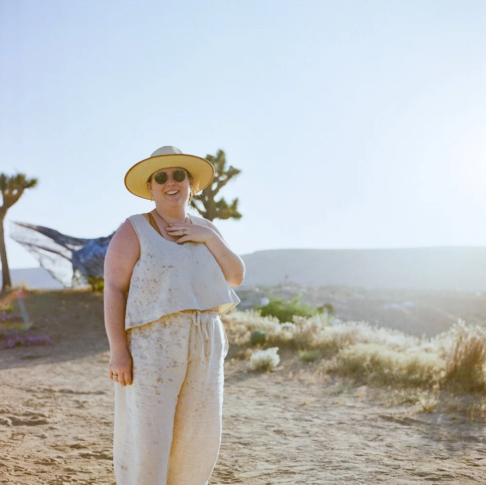 Artist in desert with Joshua tree and painted art in background