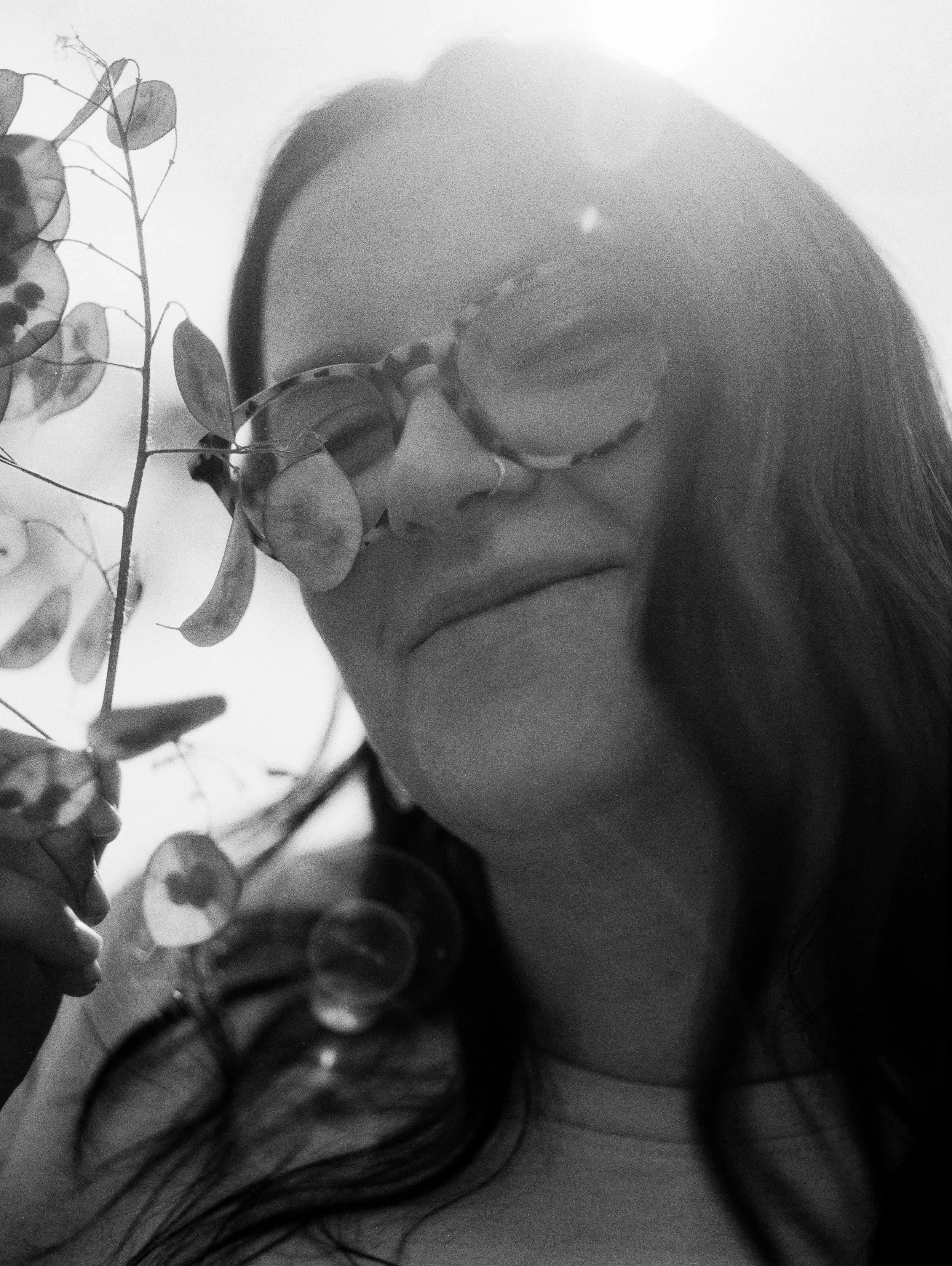black and white grainy portrait of woman with lunaria dried silver dollar plant