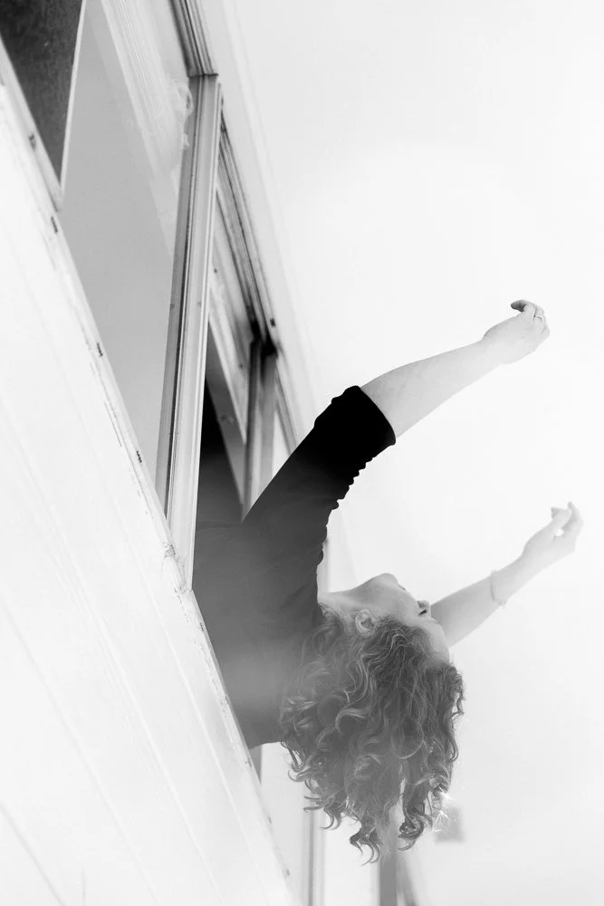 portrait of woman leaning out open window