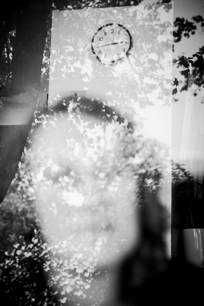 woman's reflection below clock at 2:45