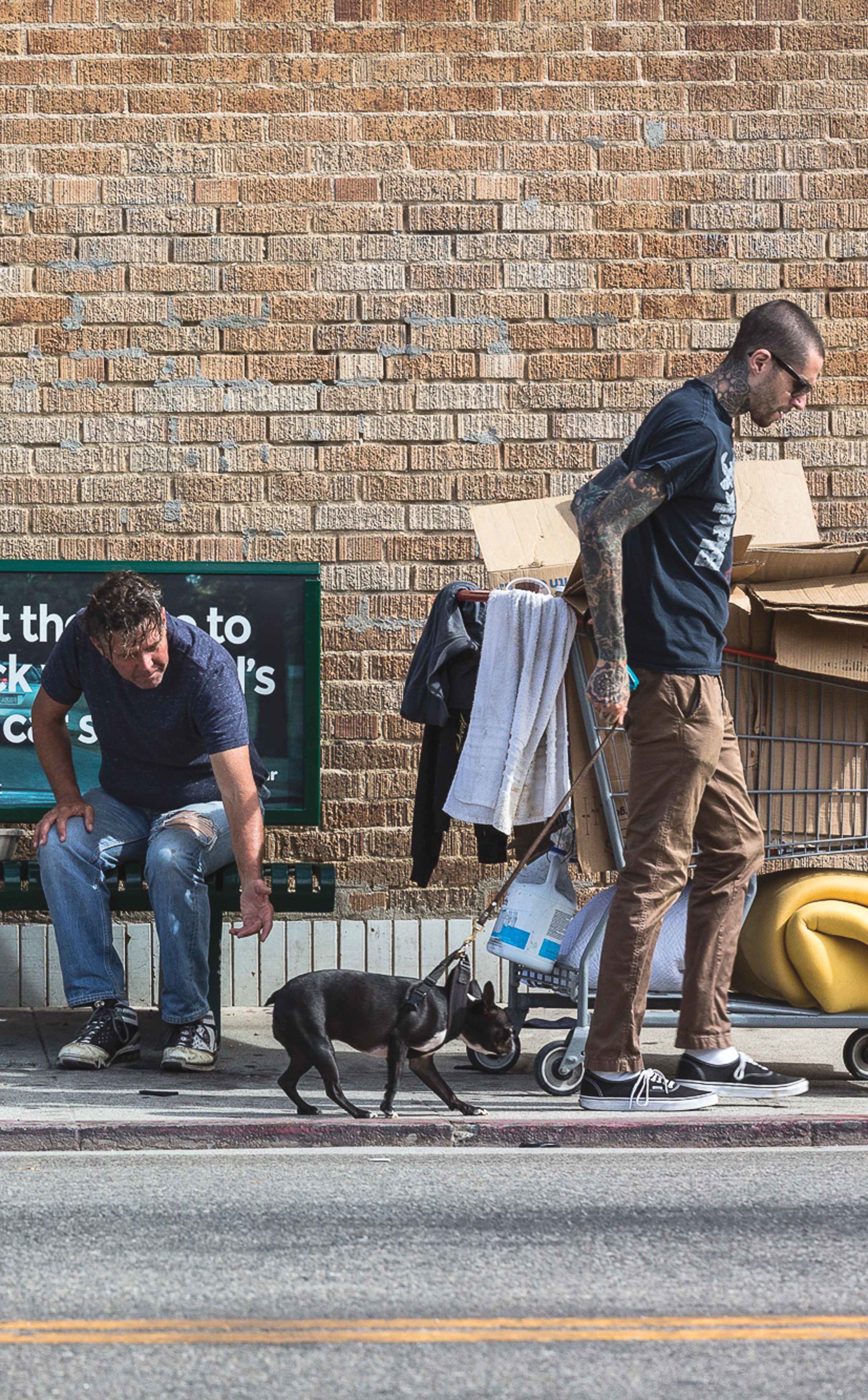  Floyd (left), 55, a frequent roamer of Venice streets attempts to pat a local hipsters dog as it is pulled away by the owner on Westminster Ave in Venice, CA on October 16, 2016. The photograph illustrates the overlooked past and privileged present 