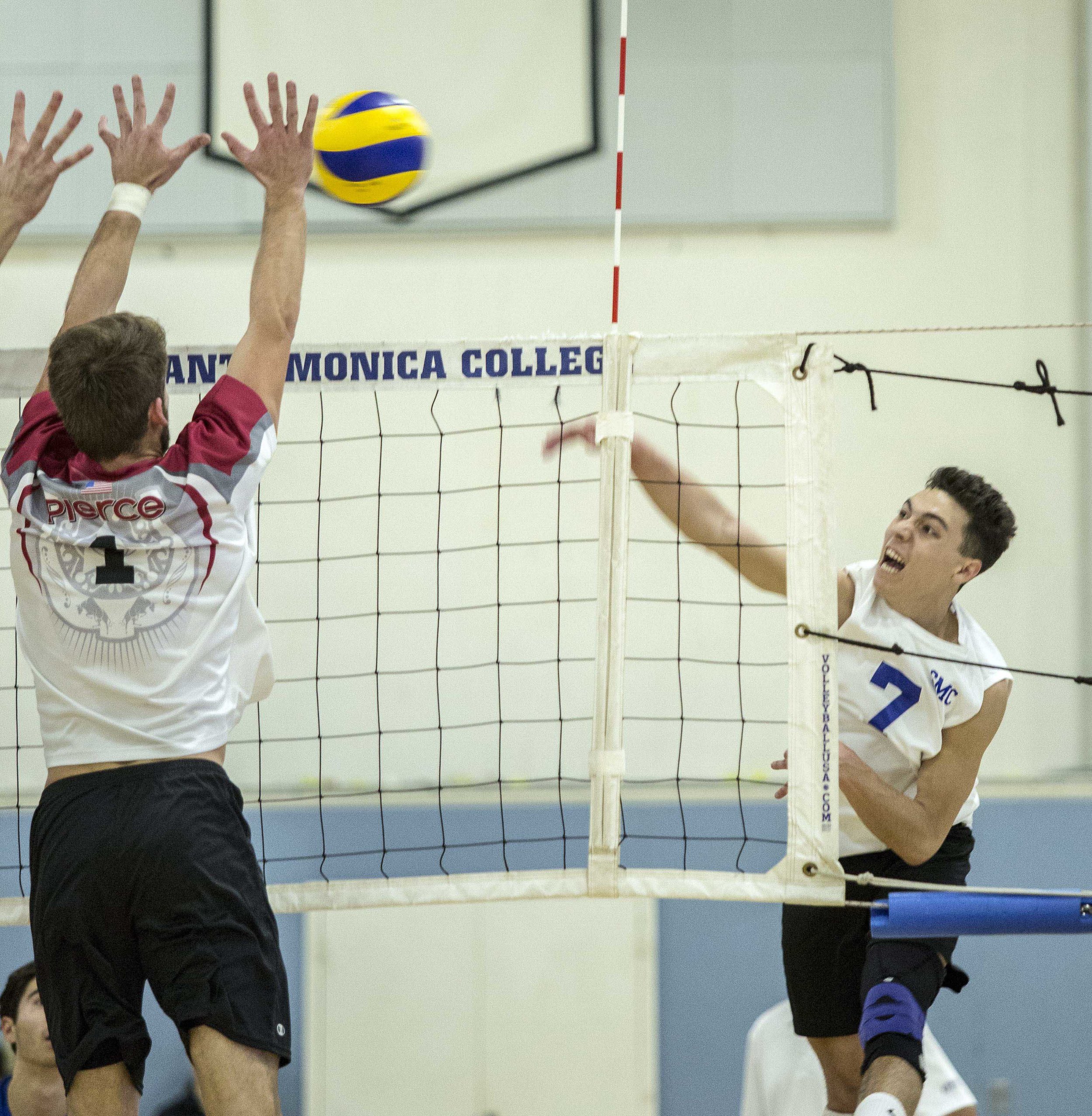  Santa Monica College Corsair freshman outside hitter Max Bell  (7, right) spikes the ball as the Pierce College Brahmas freshman opposite hitter Brandon Oswald (1, left) attempts to block the ball in the SMC gymnasium at Santa Monica College in Sant