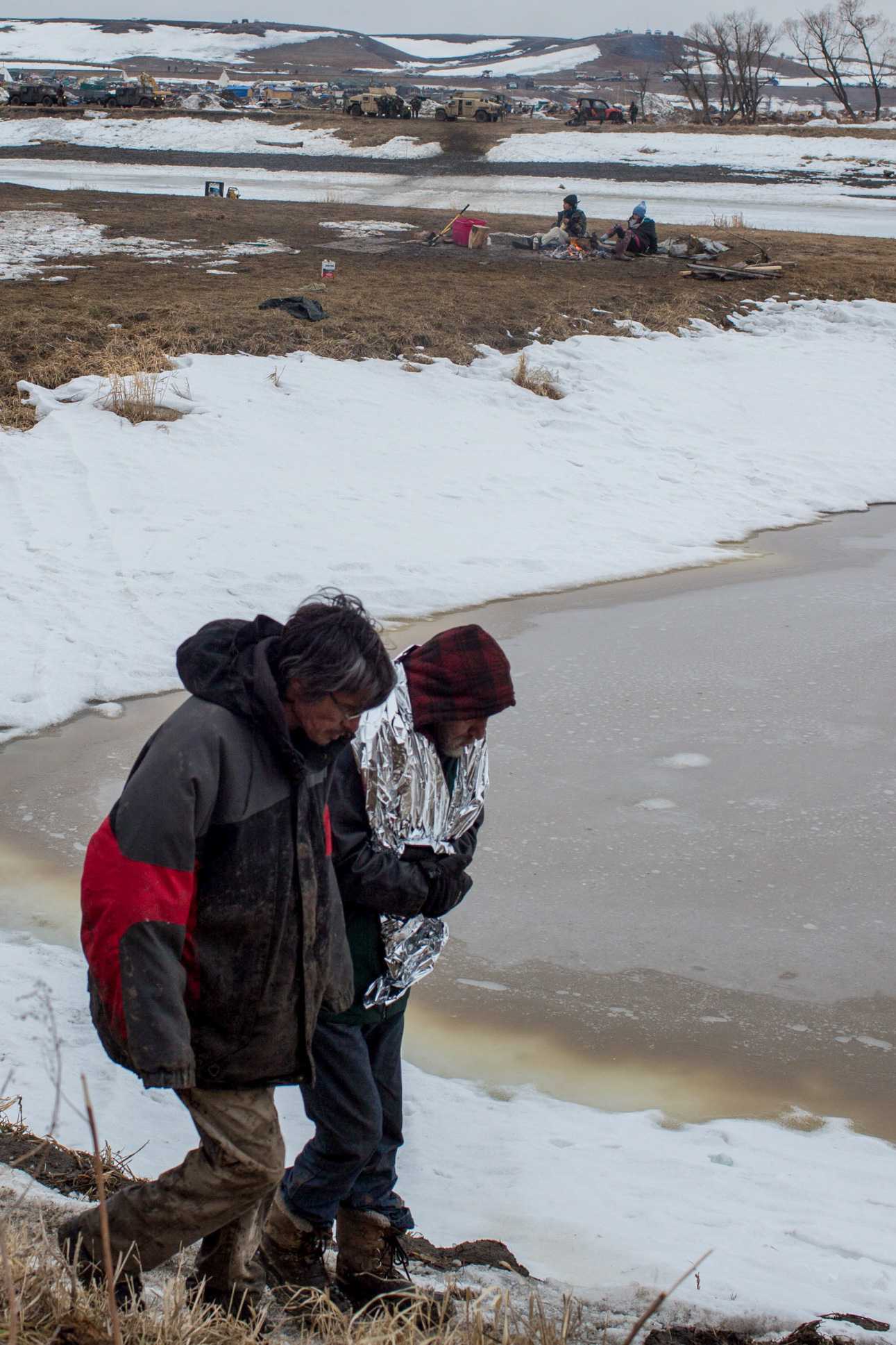  Elders retreat as in the distance hundreds of heavily militarized and armed police raid Oceti Sakowin camp, the protest camp established by the seven councils of the Lakota tribe in order to resist the proposed Dakota Access Pipeline. Photo by Ruth 