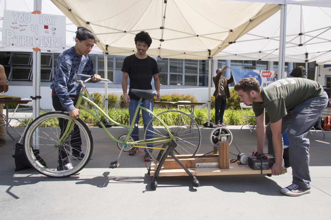  Bike Club sets up their charging bicycle for Earth Week at Santa Monica College on April 18, 2017. Justin Okobu Bike Club member (center) watches as Henry Haprov, who built the stationary bike that charges as you pedal, move it into the shade. Stude