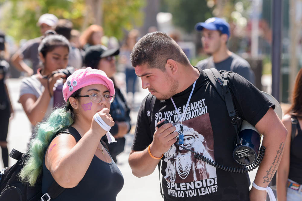  Estephanie Guardudo (left) and Edgar Gonzalez (right) share a quick conversation as protesters march through Santa Monica College Main Campus' Quad in Santa Monica, Calif. (Photo by: Clyde Bates) 