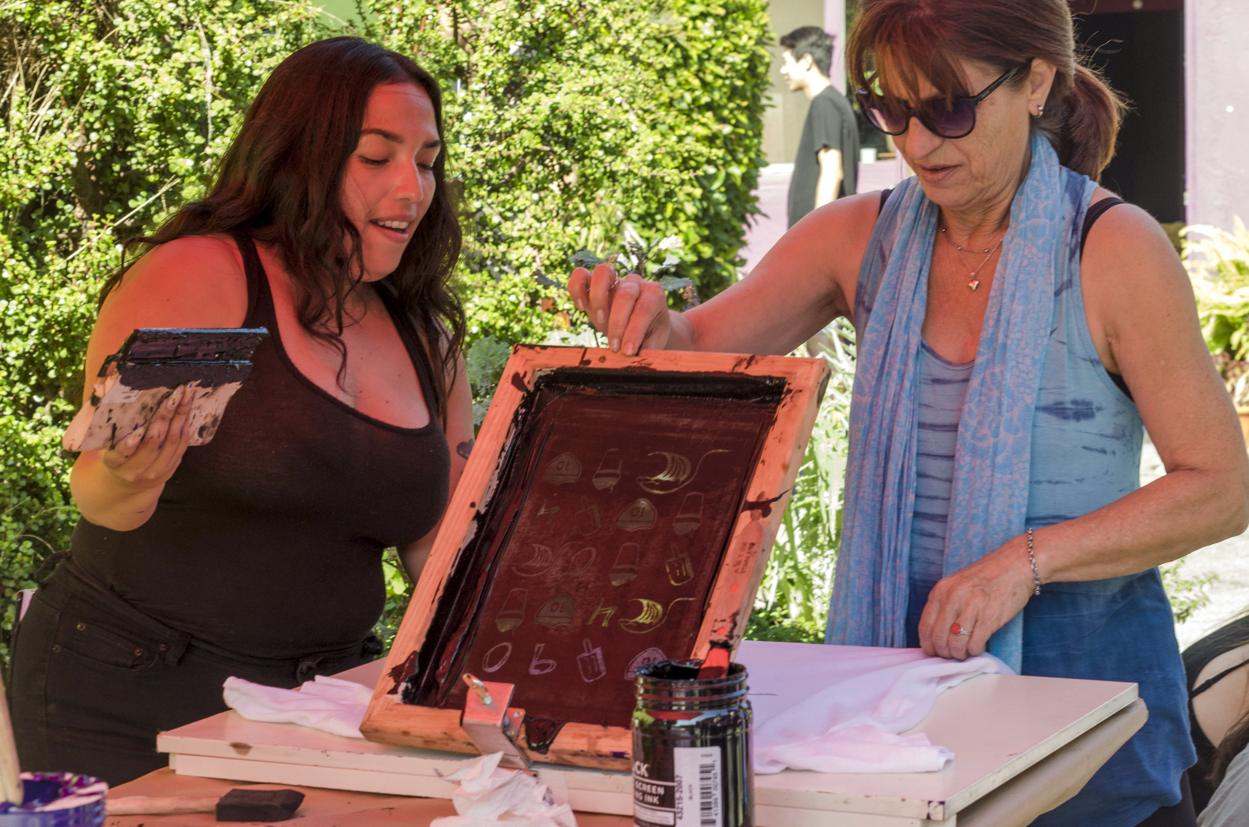  Free T-shirts to screen print were done at the Pico Block Party. Christina Saucedo (left) showing a participant of the Pico Block Party how to screen print. 18th Street Art Center on 18th and Olympic. Santa Monica, Calif. October 14, 2017. (Photo by