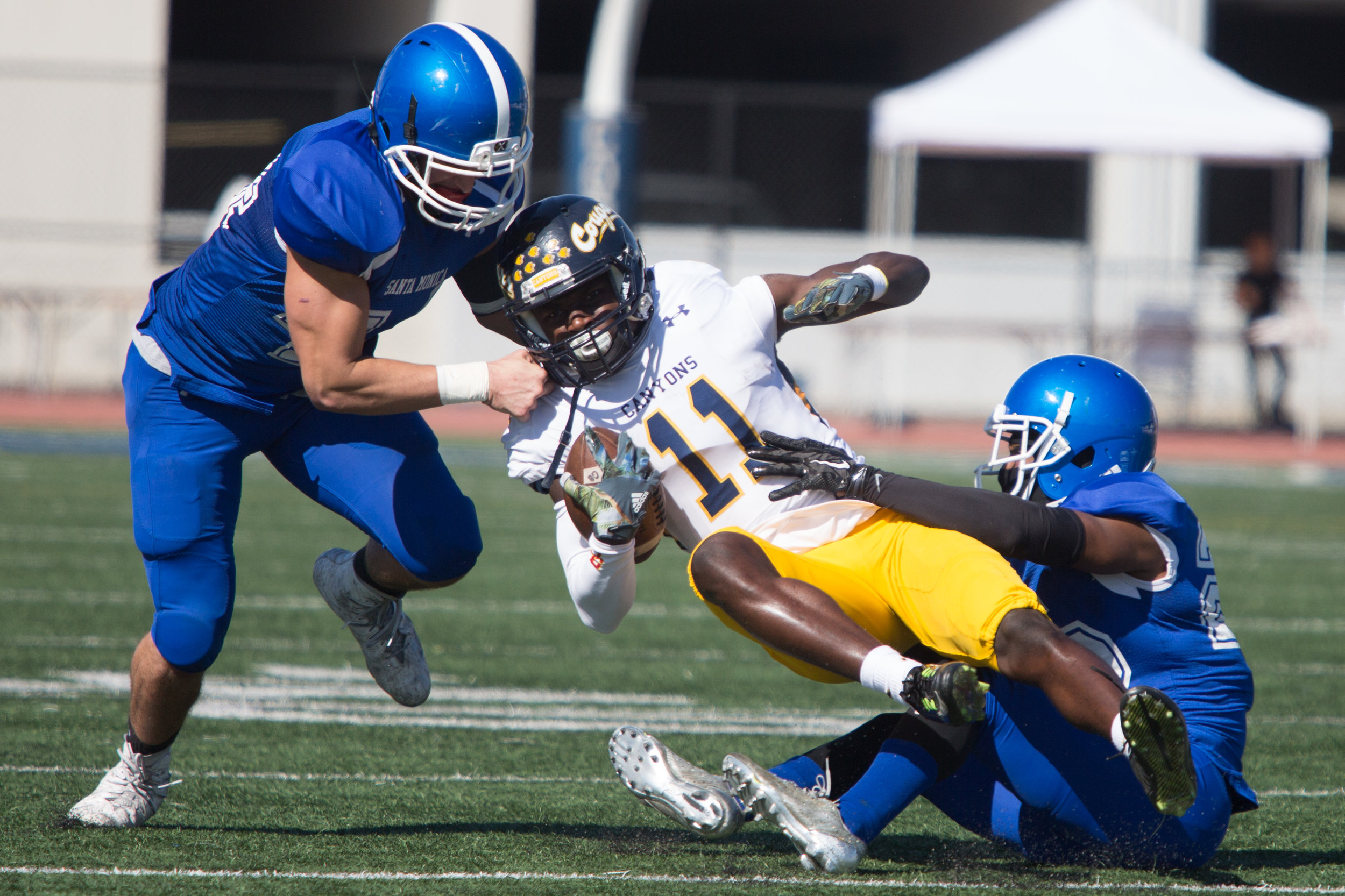  Linebacker Chris Wein (44, Left) and Defensive back Richard Harbor III (22, Right) of Santa Monica College Corsairs attempt to tackle Wide receiver Jarrin Pierce (11,Middle) of College of the Canyons Cougars during 2nd quarter of their homecoming ga