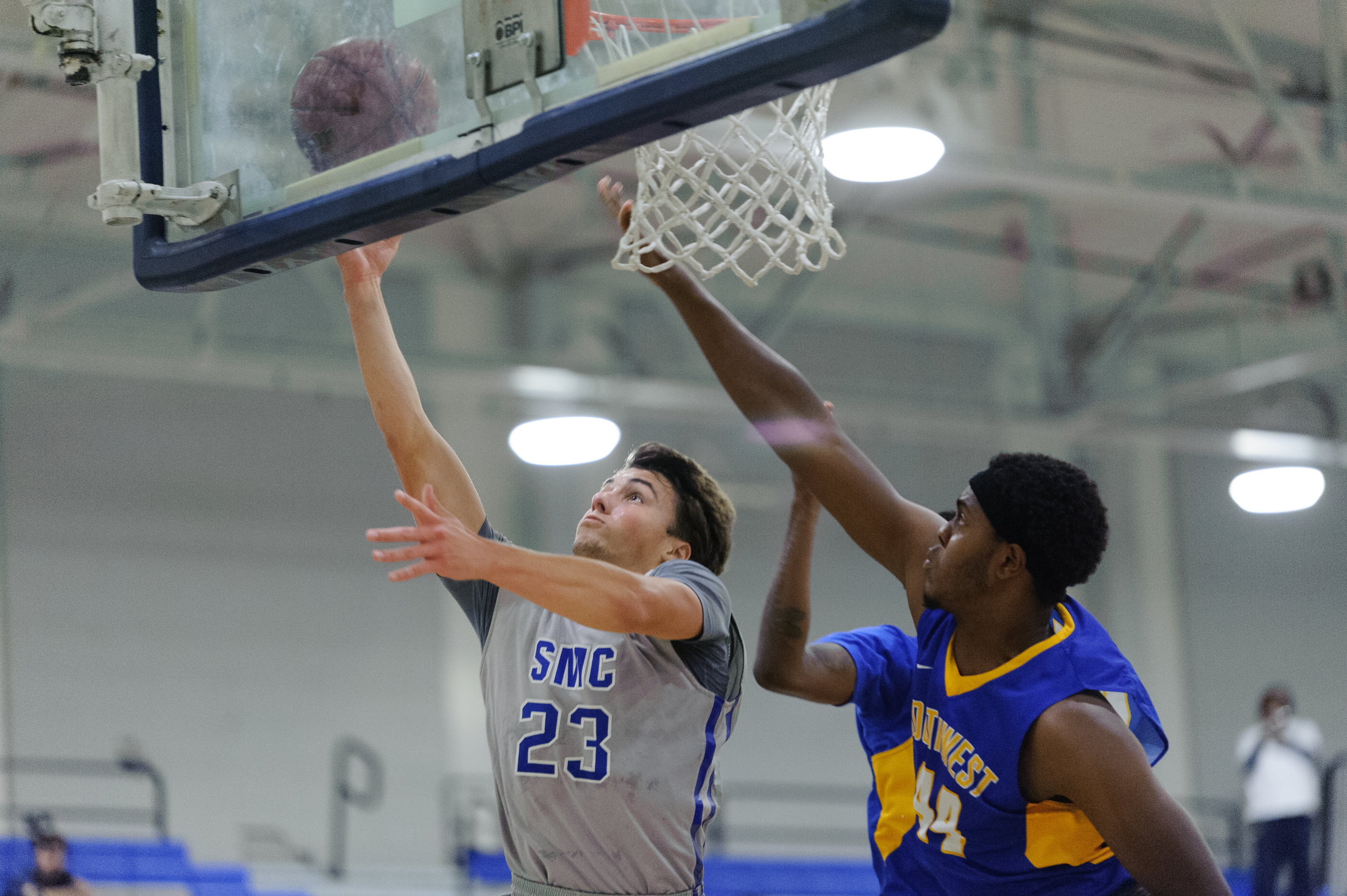  Forward Dayne Downey (23,Left) of Santa Monica College shoots a contested layup away from the outstretched hands of forward Malik Muhammad (44,Right) and guard D’Lano Beckles (3,Back) of Southwest College. The Santa Monica College Corsairs win their