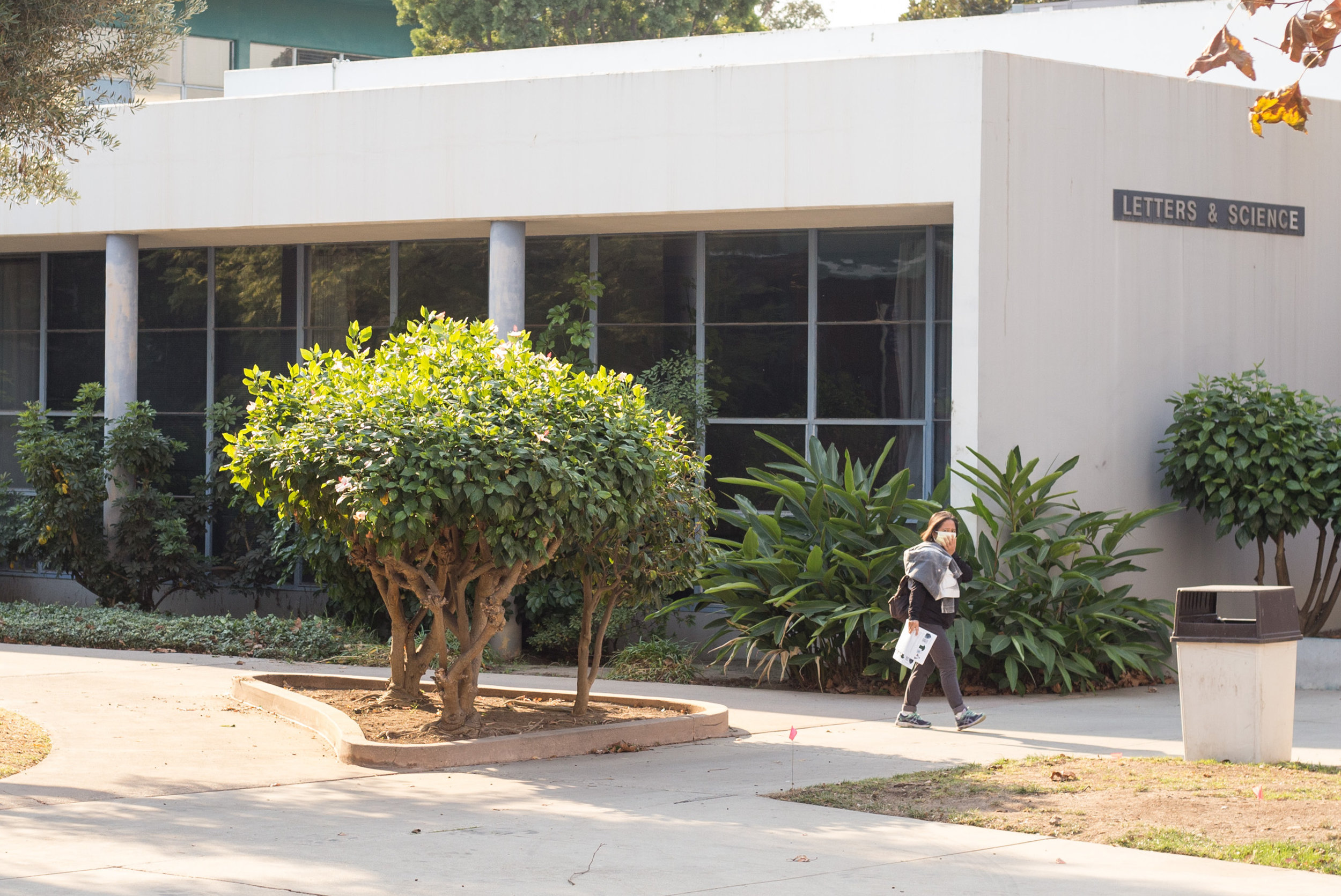  A Santa Monica Student walks by the Letters & Science building on SMC's main campus. She is wearing a mask because of the poor air quality from the Skirball fire. An email was sent to all students at 8:49 am informing students that classes are cance
