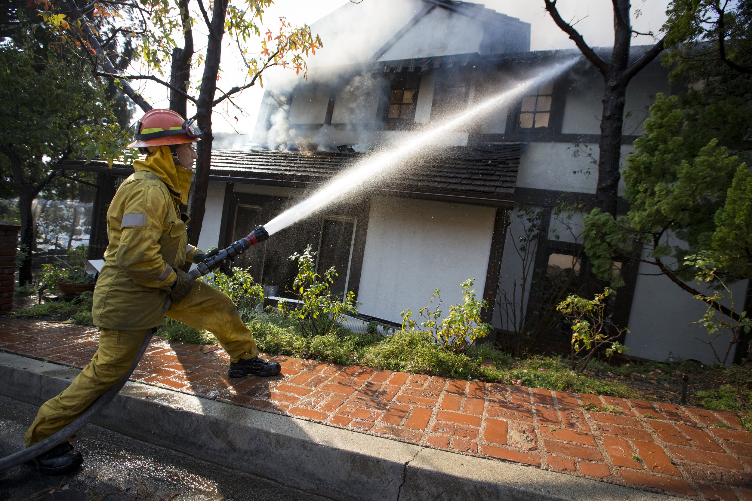  Los Angeles Fire Department engine company 71 firefighter David Valadez readies a hose to put out the flames of a burning house at The Skirball Fire which shut down the 405 north and burned 450 acres of land on Dec.&nbsp;6, 2017 in west Los Angeles,