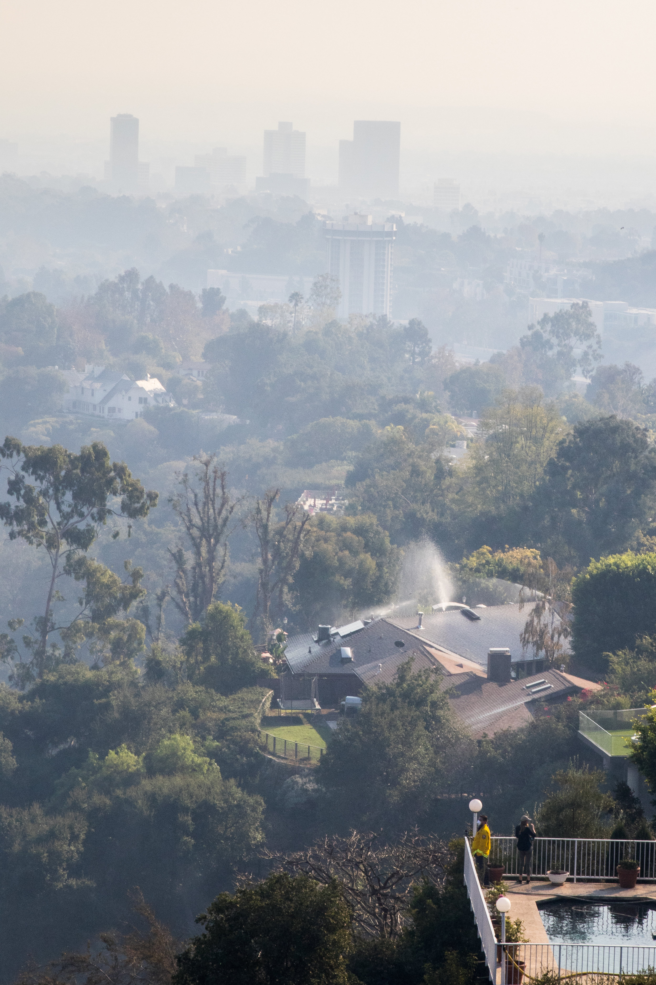  A member of the Los Angeles Fire Department and one of the many homeowners look out at the smoke filled West Los Angeles Skyline, after the fire departments initial battle with the Skirball Fire. The fire burned 450 acres and shut down the 405 freew