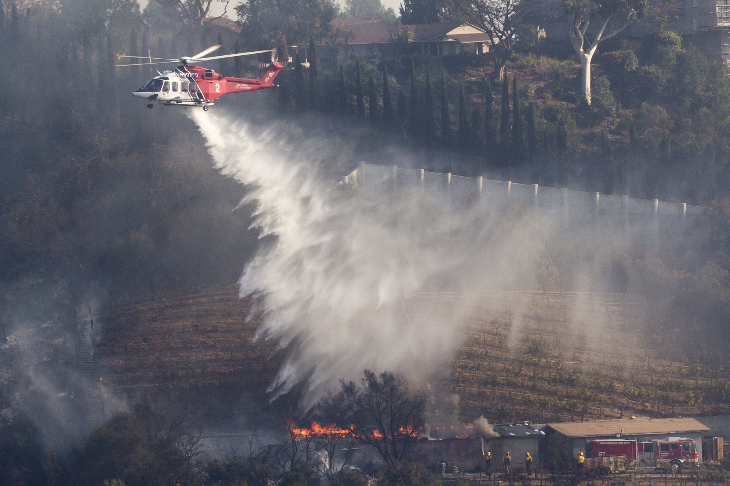  A Los Angeles County Fire helicopter makes a water drop on the Moraga Bel Air Vineyard,&nbsp;during the Skirball Fire as firefighters on the ground work to keep the fire away. On Wednesday, Dec.&nbsp;6, 2017 in the Bel-Air area of Los Angeles, Calif