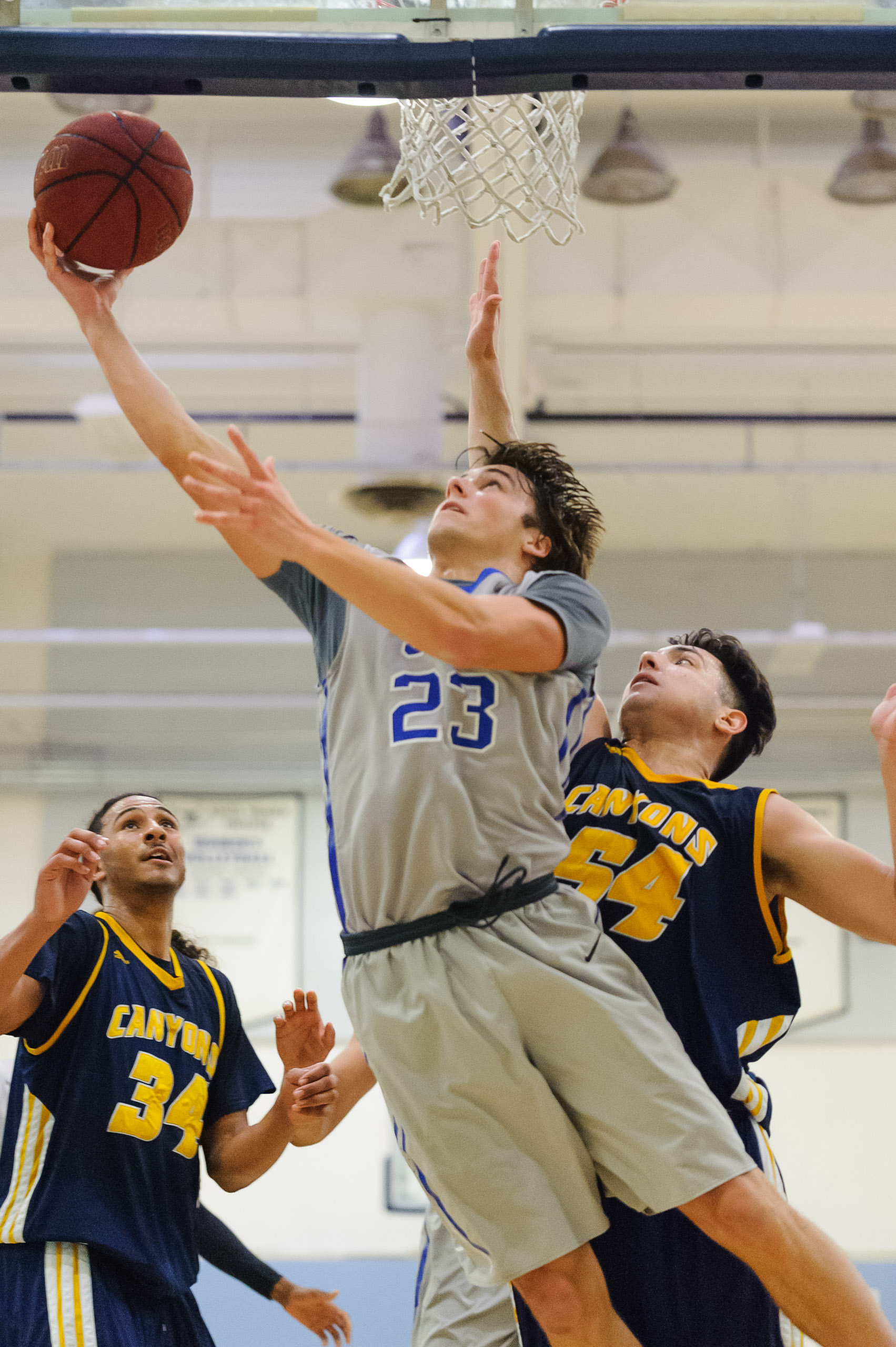  Forward Dayne Downey (23,Middle) of Santa Monica College goes up for a reverse layup while guarded by Anthony Simone (54,Right) of the College of the Canyons. The Santa Monica College Corsairs lose the game 74-72 to the College of the Canyons Cougar