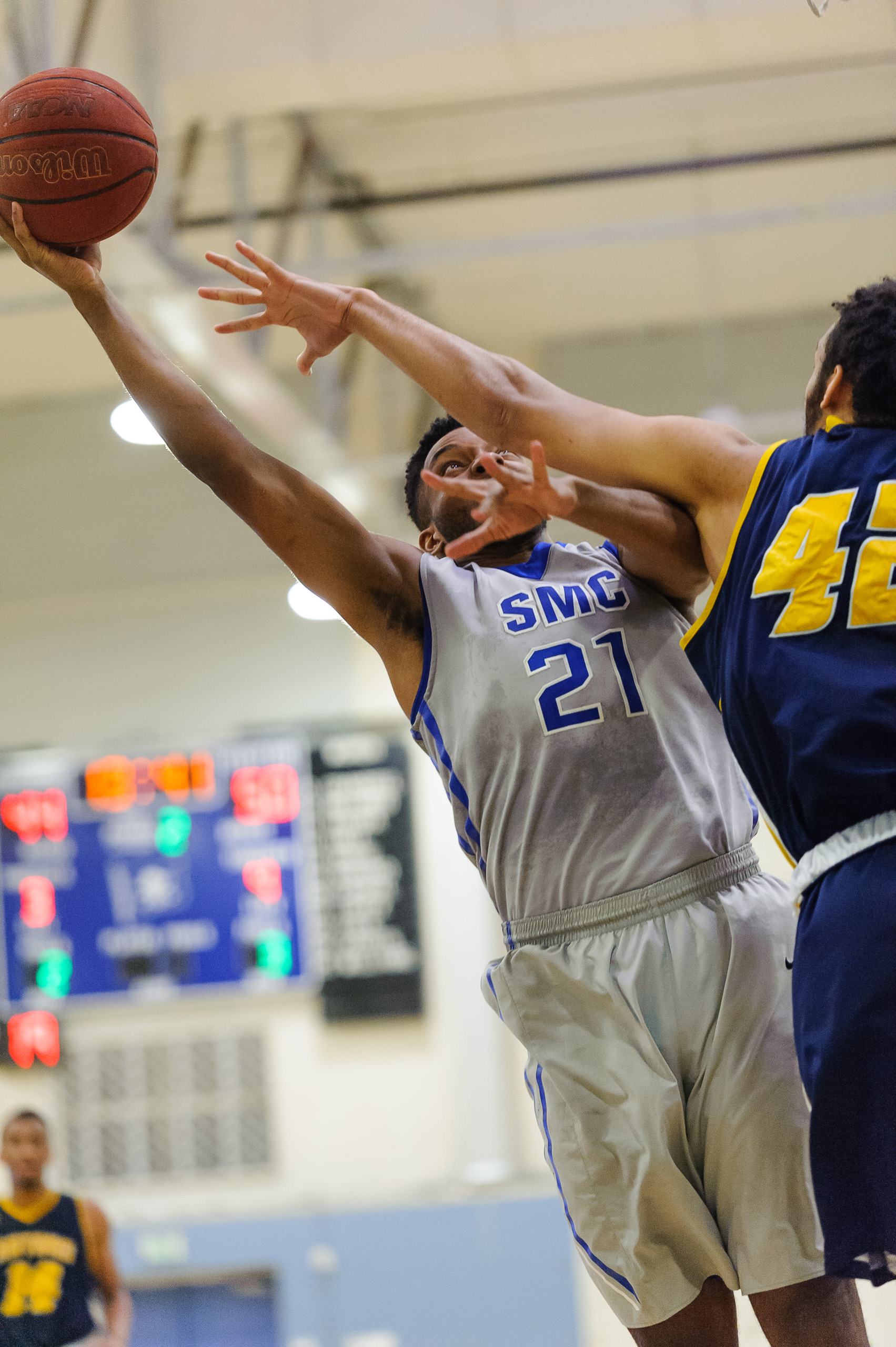  Forward Khalil Taylor (21,Left) of Santa Monica College attempts a layup while contested by Philip Webb (42,Right) of the College of the Canyons. The Santa Monica College Corsairs lose the game 74-72 to the College of the Canyons Cougars. The game w