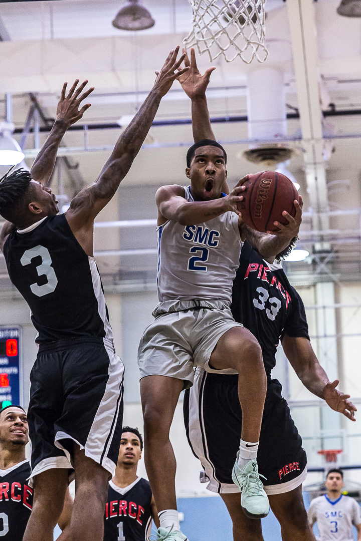  Santa Monica Corsair sophomore guard Joe Robinson #2 (middle, gray) goes for the contested layup while guarded by Pierce College Brahma Bull sophomore shooting guard #3 Chance Cole (left, black) and sophomore forward #33 Drion Graham (right, black) 