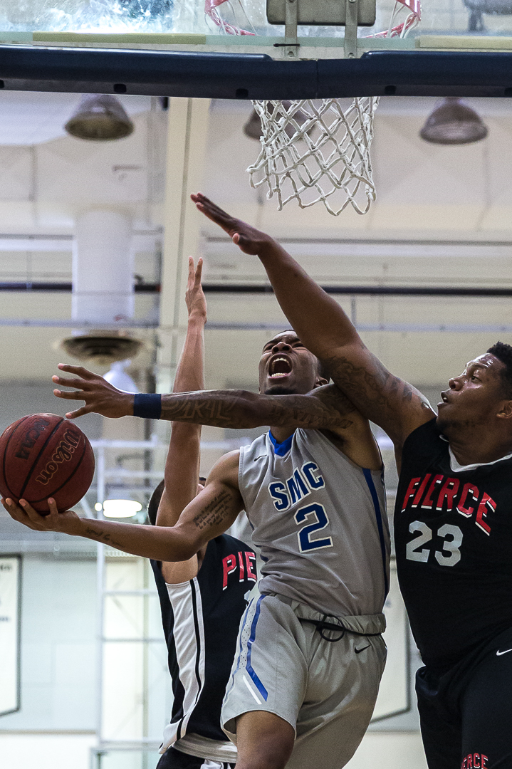  Santa Monica College Corsair sophomore guard Joe Robinson #2 (middle, gray) goes for a reversed attempted layup while being blocked by Pierce College Brahma Bull freshman guard Rashaad Johnson #23 (right, black) during the Corsairs’ 103-91 loss to t