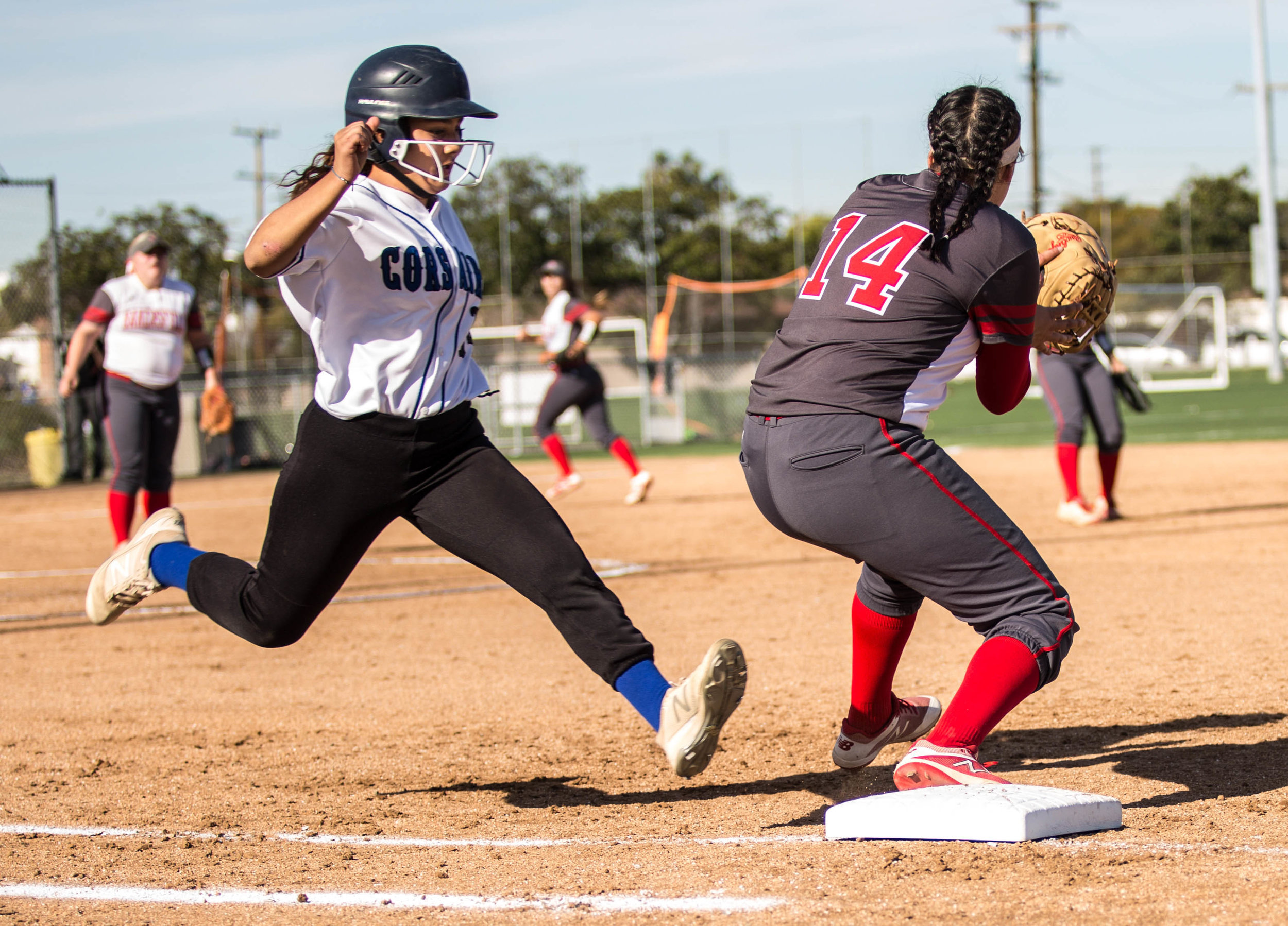 Santa Monica College Corsair freshman batter Jen Baca #14 (left, white) successfully takes first base as Bakersfield College Renegade sophomore infielder Aryka Chavez #14 (right, red) fails to tag Baca, who is declared safe, during the top of the 5th inning at the Santa Monica College Corsair Field in Santa Monica California, on Tuesday, March 6, 2018. The Corsairs would go on to lose the game to Bakersfield College 0 – 9, making their tally for the season 6 wins and 11 losses. (Corsair Photo: Matthew Martin)