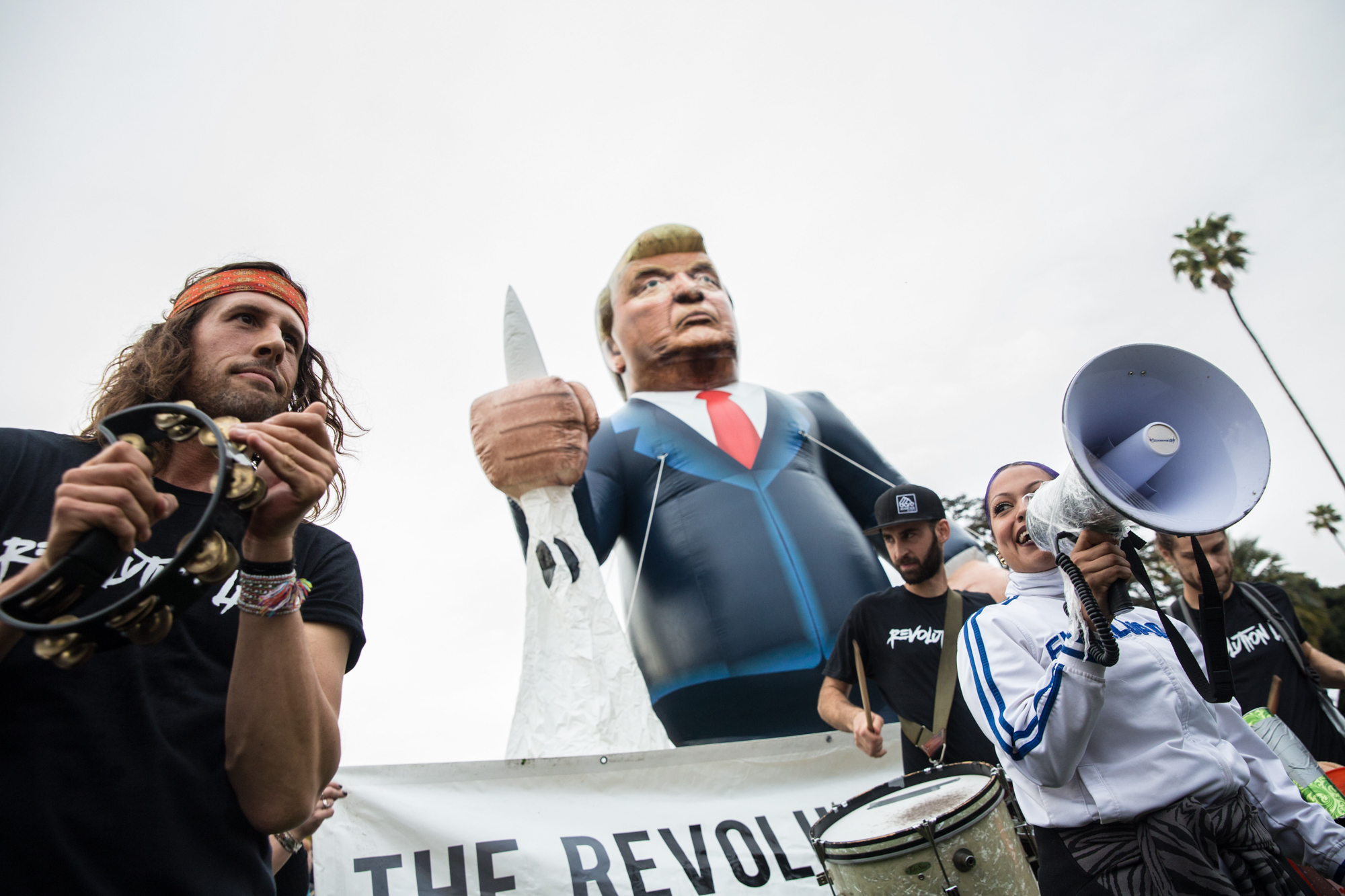 Daniel McCollister (left), member of Revolution LA, plays the tambourine to a beat that would give anti Trump supporter Alexis McCoy (right) (cq) a beat to start chanting during the Los Angeles Anti-Trump rally that took place in Beverly Gardens Park, in Beverly Hills California on Tuesday, March 13, 2018. (Photo by: Matthew Martin)