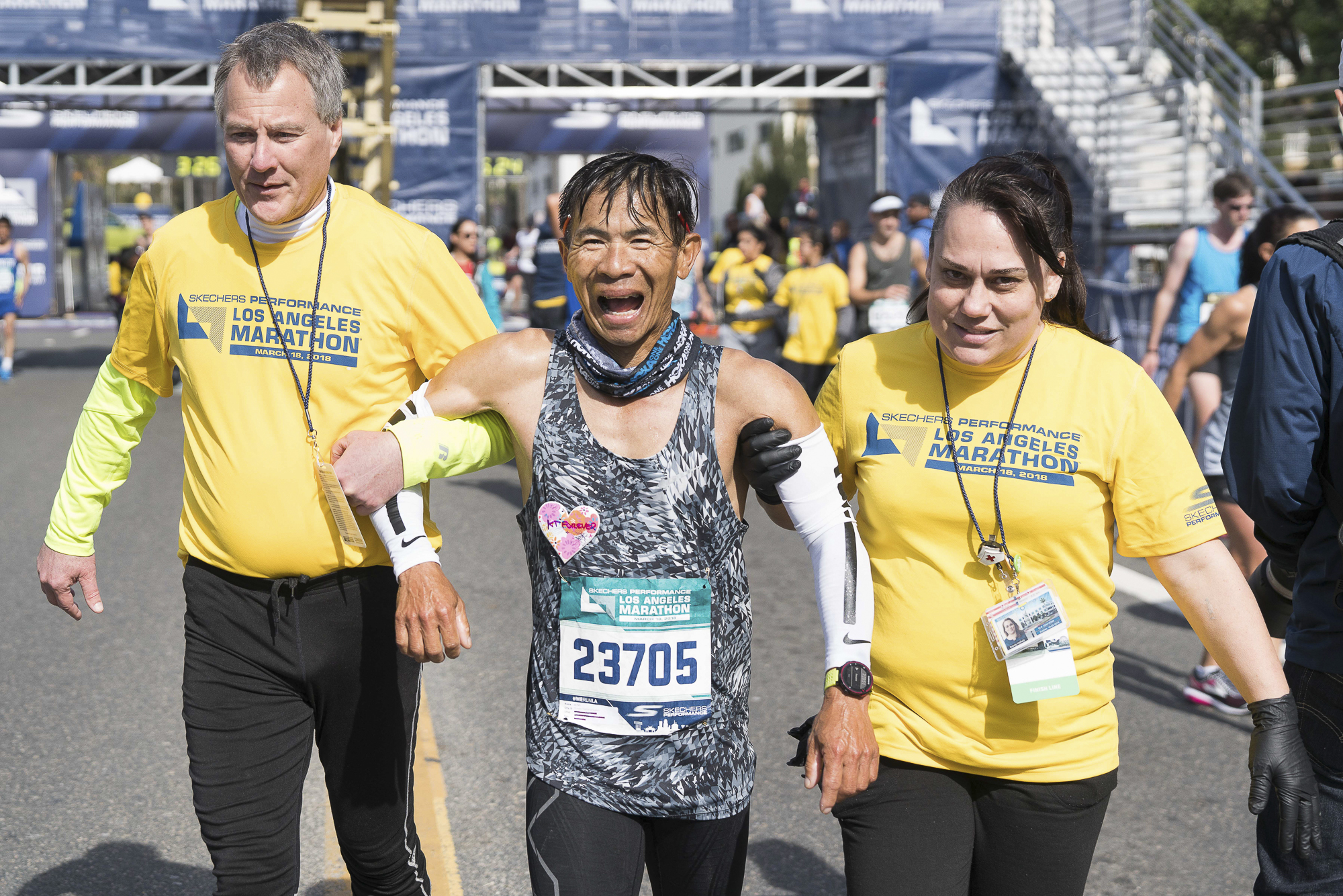  Thavee Nantarjanaporn (center) is helped at the finish line at the Los Angeles Marathon in Santa Monica, California on Sunday, March 18, 2018. Volunteers wearing yellow shirts stood ready to help runners after they completed running 26.2 miles. (Pho