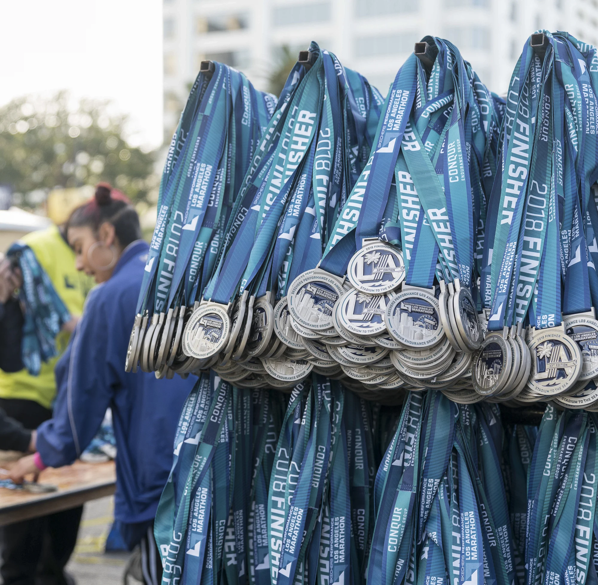 Los Angeles Marathon volunteer, Karen Arriola, unboxes and hangs medals in Santa Monica, California on Sunday, March 18, 2018. It is estimated that 24,000 people participated in the marathon this year. (Photo by: Helena Sung).