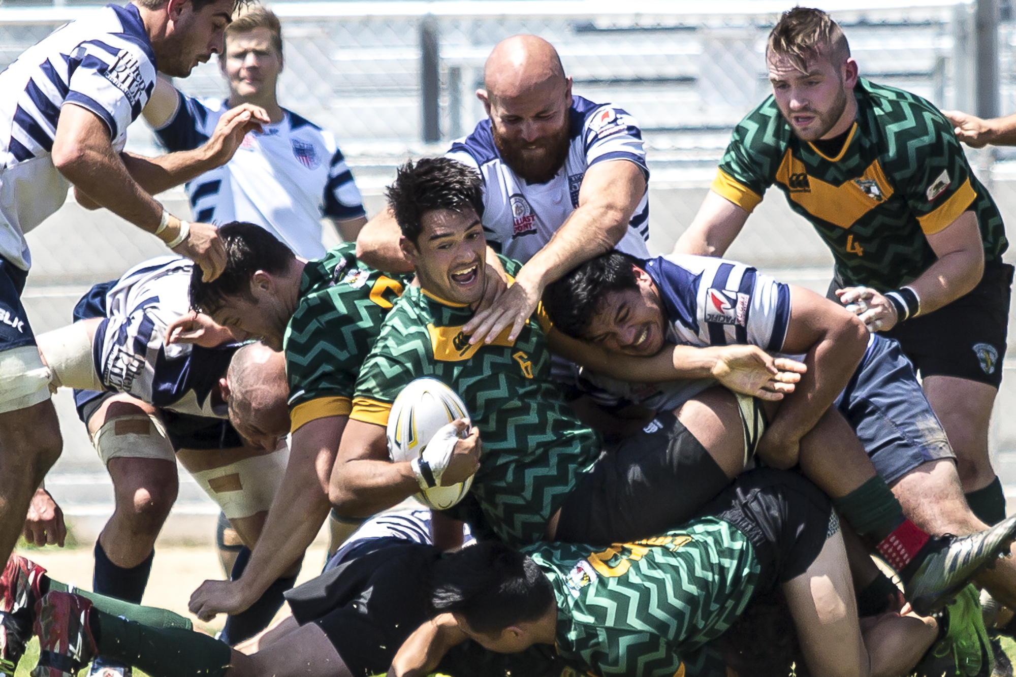  Santa Monica Dolphin Chris Allman #6 (center, green) is dog piled by Old Mission Beach Athletic Club (OMBAC) defense while being pushed by his Santa Monica Dolphin teammates at Westchester High School field in Westchester California on Saturday Apri