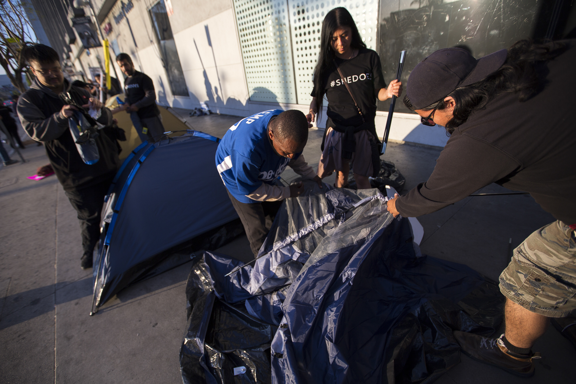  Joe Dominguez (right) and Teresa Chuc (center right), who are part of the #SheDoes movement to push for more housing for homeless women and children, work with Darryl Robinson (center left) to break down one of the tents used during the demonstratio