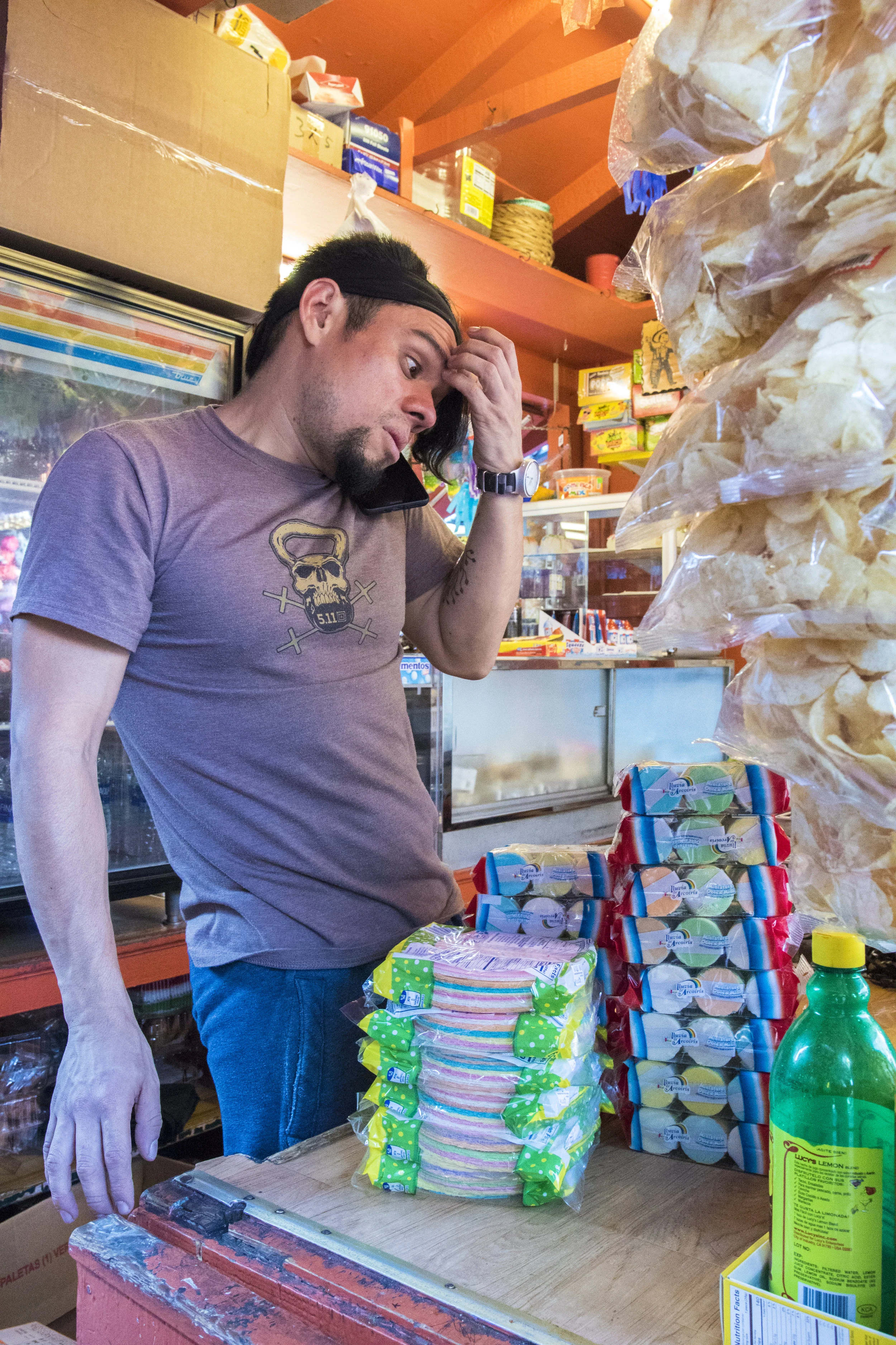 Frank Franquis, an employee on Olvera Street, restocks his work space at Rudys Mexican Candy after an extremely busy weekend that he described as "200-300%" more busy than usual, while taking a phone call from his boss where she told him that she would not be coming into work, on October 29, 2018. Although business booms during the Dia De Los Muertos celebration, most other times of the year are slow. Frank has been working at this shop for the last 3 years and works from 7 am to 8 pm everyday at both Rudys Mexican Candy and Munoz Mexican Store. Even in that short time has seen a dramatic decrease in customers. He believes it is due to the neighboring homeless population who often steal items from the shops. Although he is often a victim of theft, Franquis does not hold a grudge against the homeless. As he knows they are just doing what they need to do to get by. (Zane Meyer-Thornton/Corsair Photo)