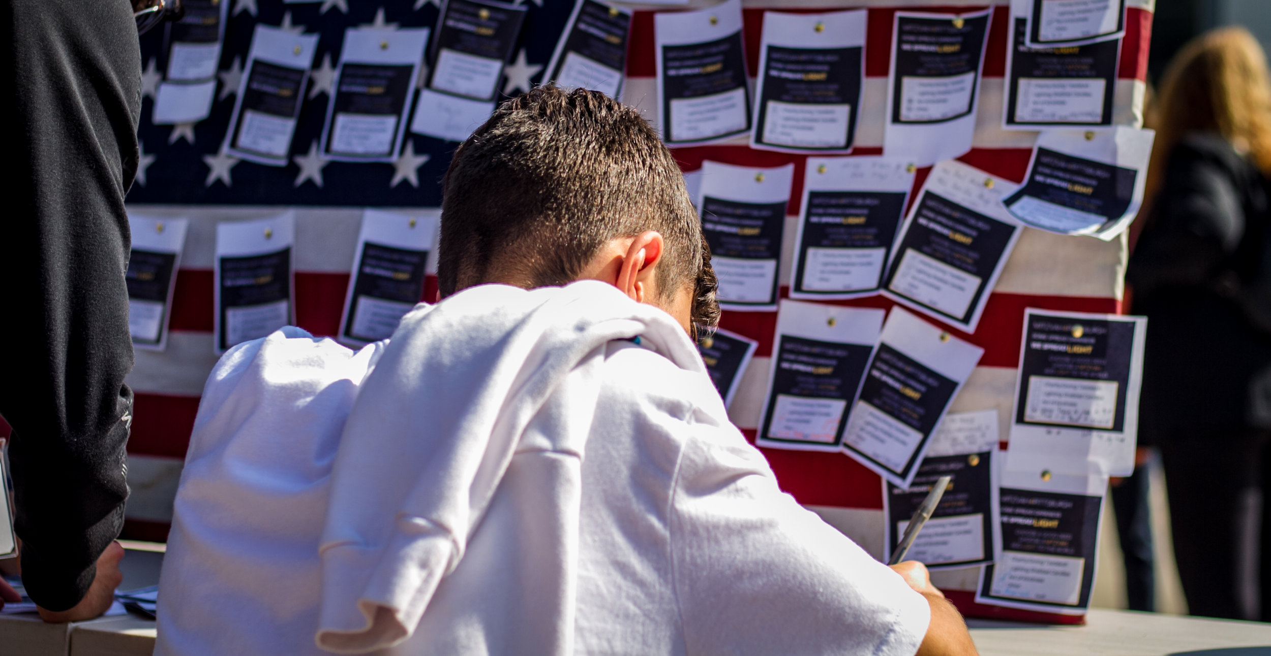  Santa Monica College (SMC) student writes down his act of kindness and goodness to pin on the American Flag. SMC's main campus on Oct. 30, 2018 (Yasser Marte/Corsair Staff) 