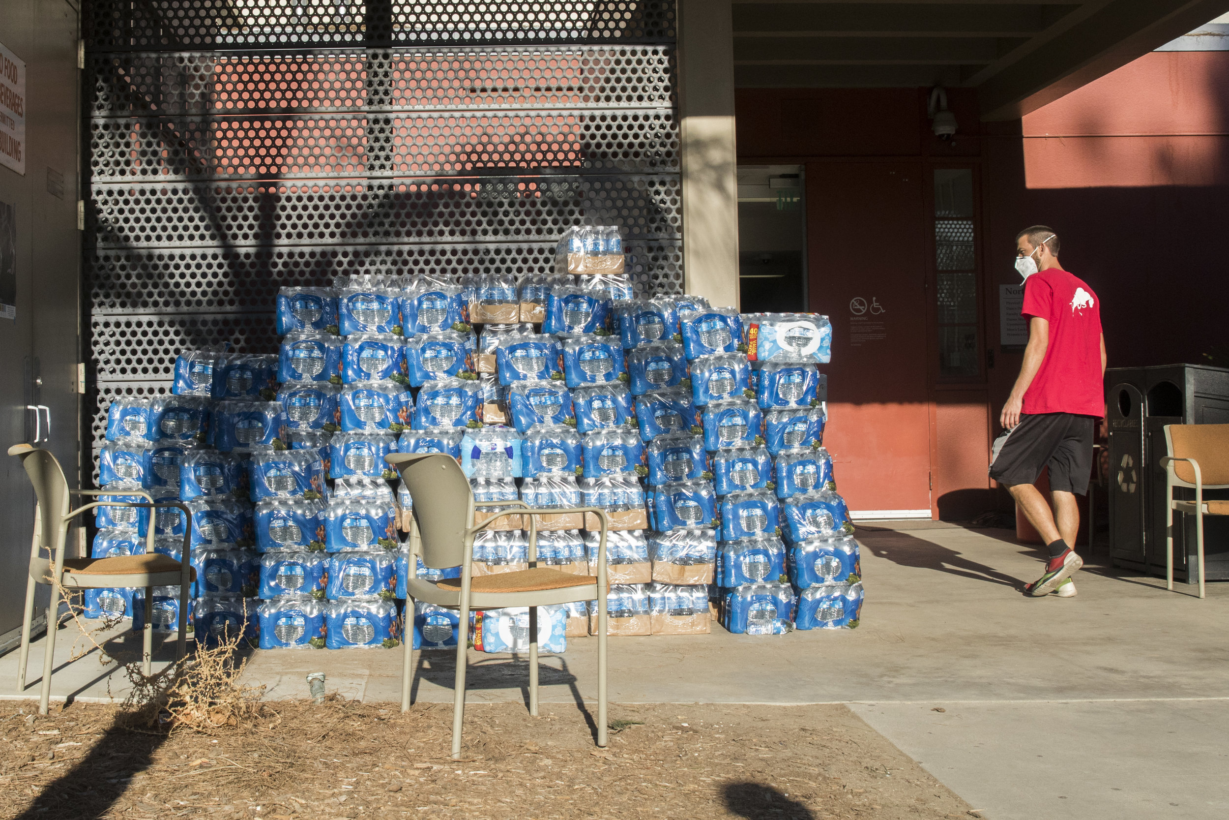  A volunteer walks by water bottles donated by Juan Mutaz (not pictured), a store manager for a Home Depot located in West Hills, California. The water bottles are readily available for any evacuee of the Woolsey Fire who have taken refuge at Pierce 