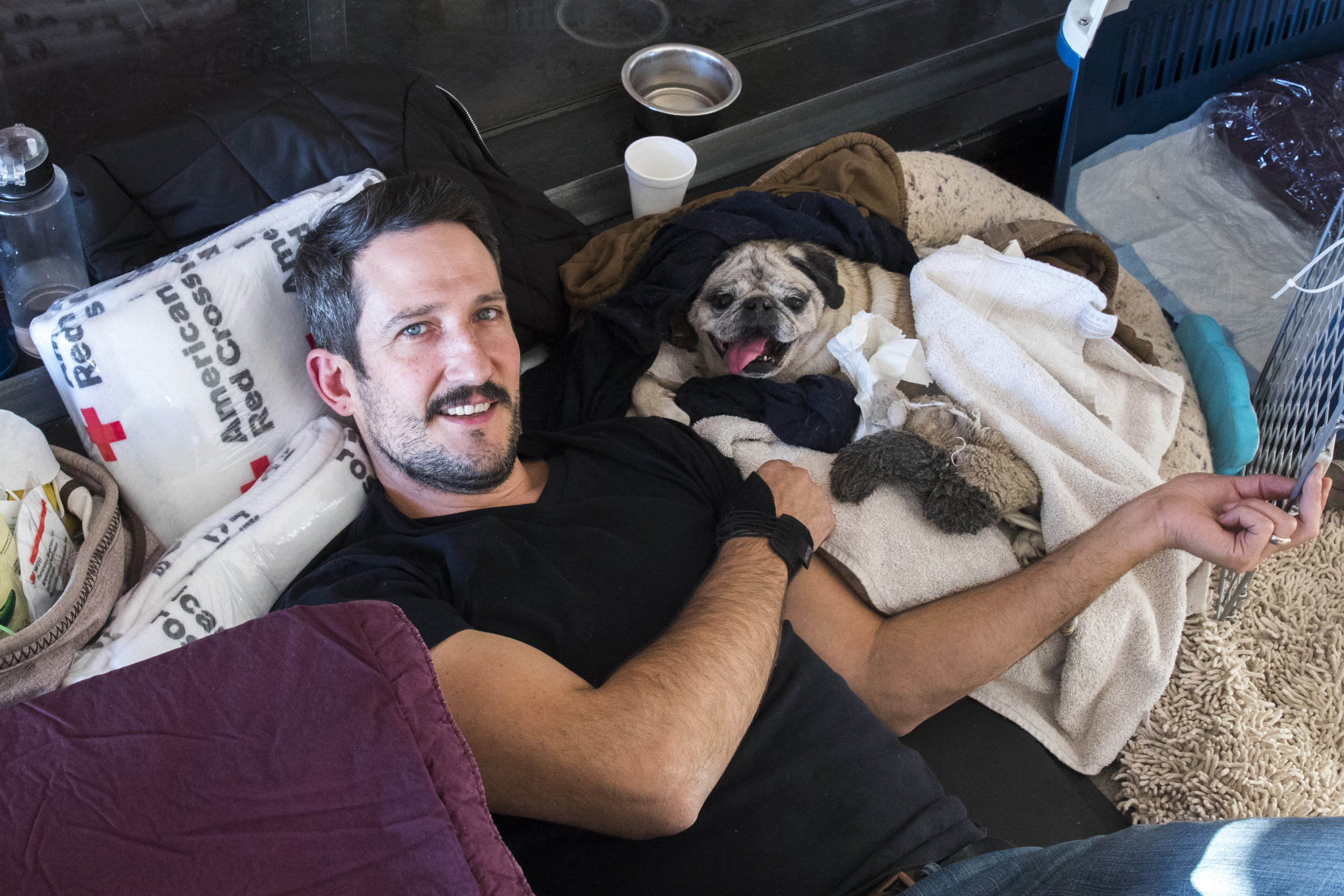  Tony D'Amore relaxes with his paralyzed dog, Bogey at an evacuatin center located at Pierce College in Woodland Hills, California on November 9, 2018. Tony said that since Bogey cannot move around due to his paralyzation, he was very happy to be at 