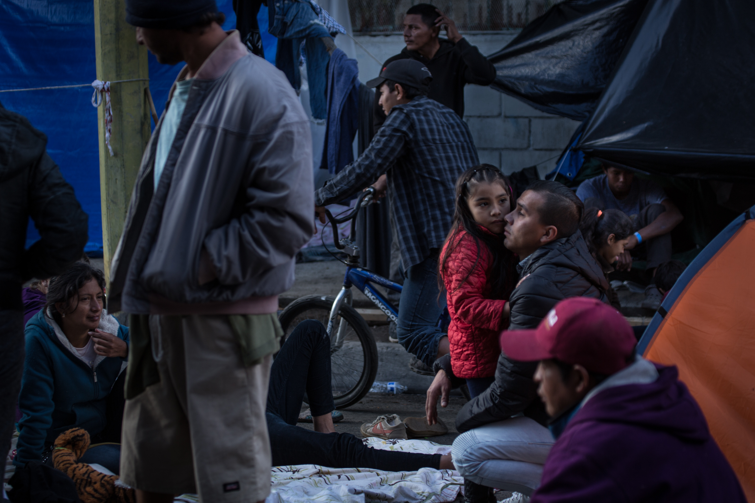   A displaced child clings to her father outside Benito Juarez sports complex in Tijuana, Mexico, Saturday, Dec. 1, 2018. Asylum seekers previously housed at Benito Juarez have been evicted and moved on Friday, Nov. 30, 2018, due to flooding from rai