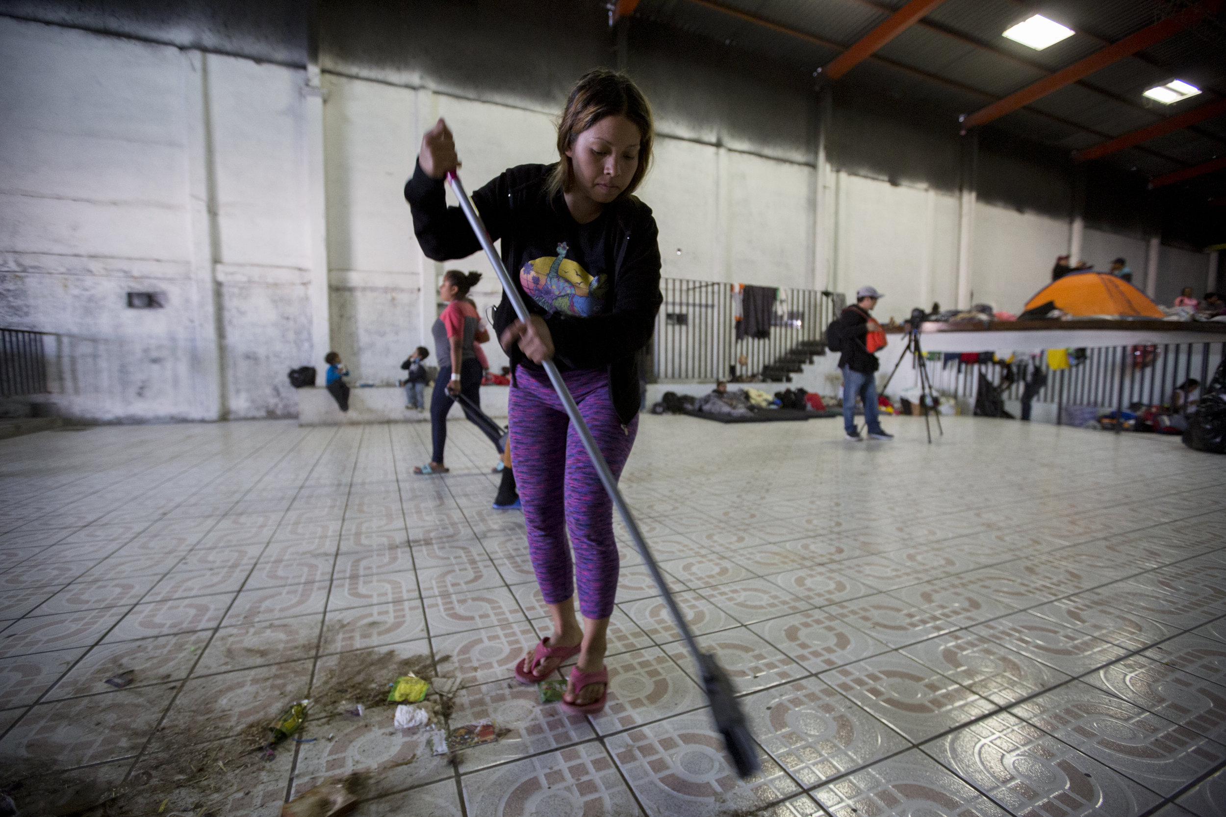   Joanna Caseres, 20, from Honduras, helps clean up the new shelter space, El Barretal, in preparation to receive evacuated Central American migrants on Saturday, Dec. 1, 2018, in Tijuana, Mexico. The new location, El Barretal, is a space that was pr