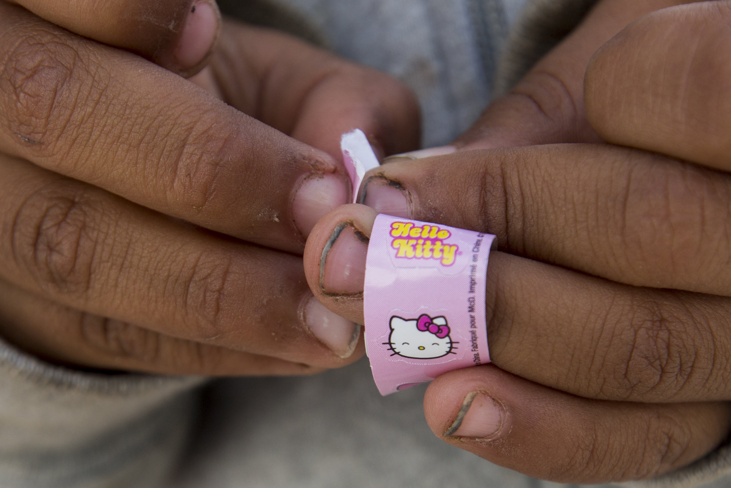   A migrant child, who has yet to evacuate with her family after the rains, plays with a roll of "Hello Kitty" stickers that she is placing on her jacket while at the Benito Juarez sports complex on Saturday, Dec. 1, 2018, in Tijuana, Mexico. Photo B