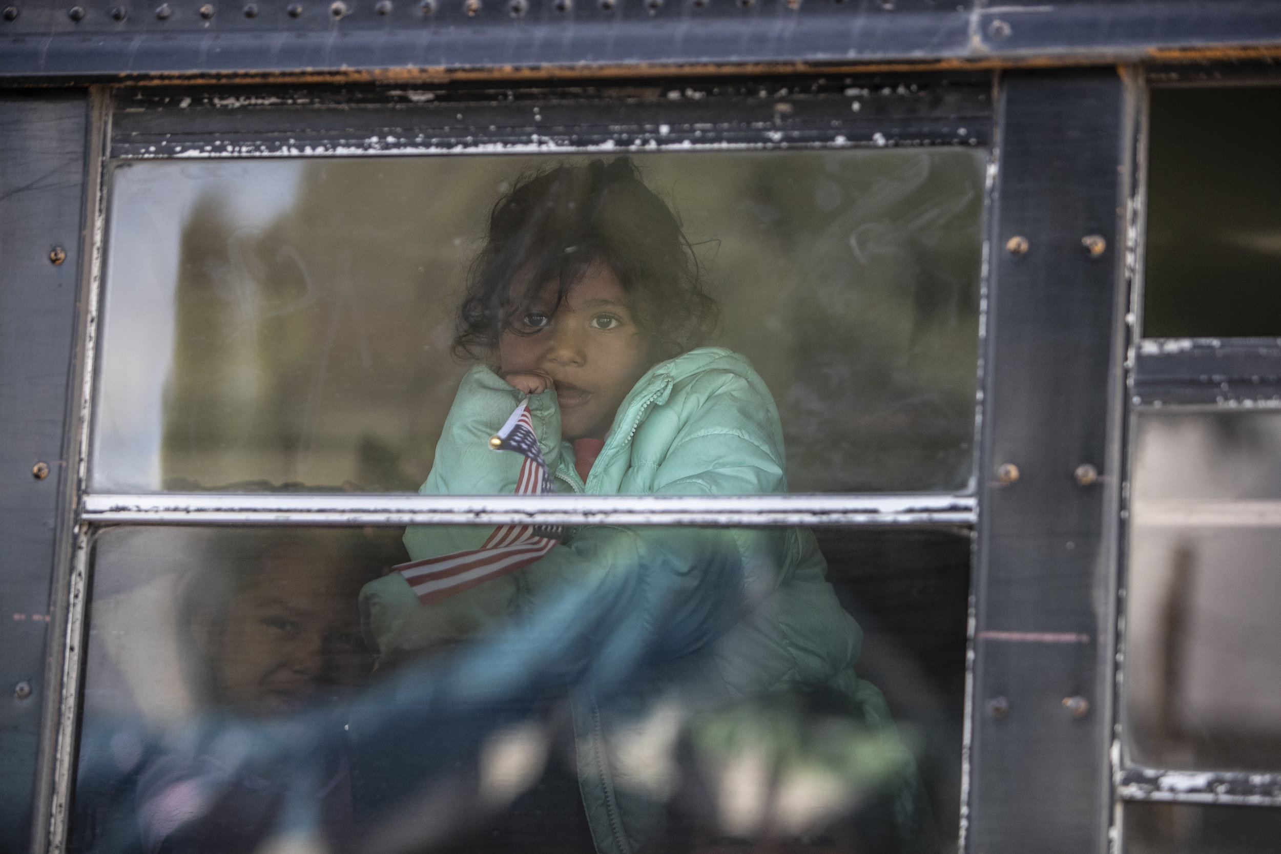   A young Central American migrant  girl carrying an American flag, being transported by bus from the Benito Juárez sports complex shelter to the El Barretal, a night club being used as a temporary shelter  in Tijuana, Mexico, Saturday, Dec. 1, 2018.