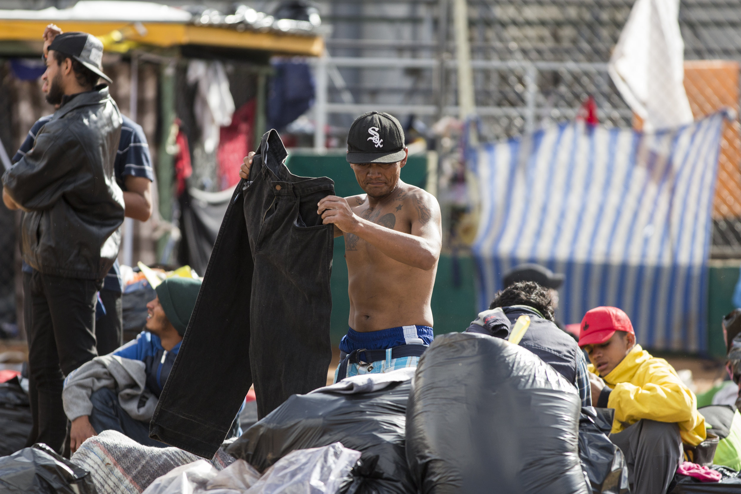   A migrant who has not yet evacuated the flooded space attempts to recover personal items at the Benito Juarez sports complex on Saturday, Dece. 1, 2018, in Tijuana, Mexico. Photo By: Jose Lopez / Corsair Contributor   