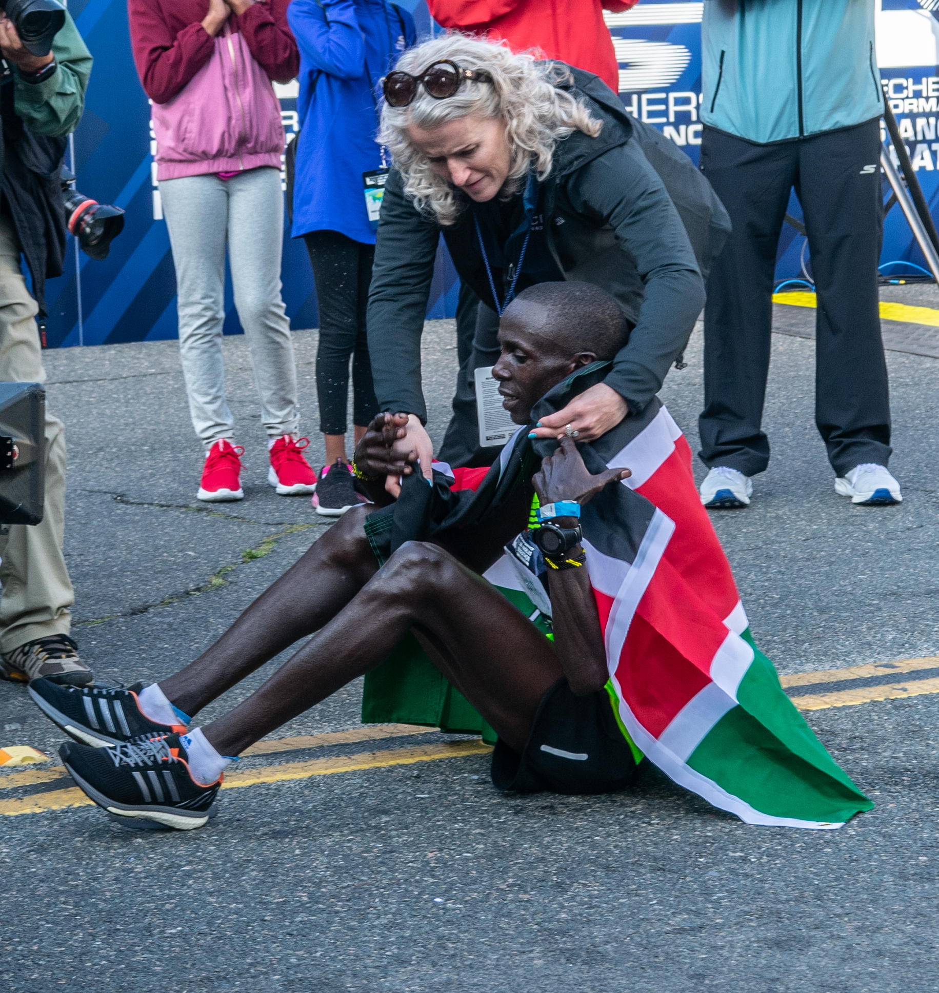 Tracey Russell, CEO of Conqur Endurance Group, placing the Kenyan flag on Los Angeles Marathon winner Elisha Barno as he is resting on Ocean Ave, on Sunday March 24th 2019, in Santa Monica Calif. (Conner Savage Corsair Staff).