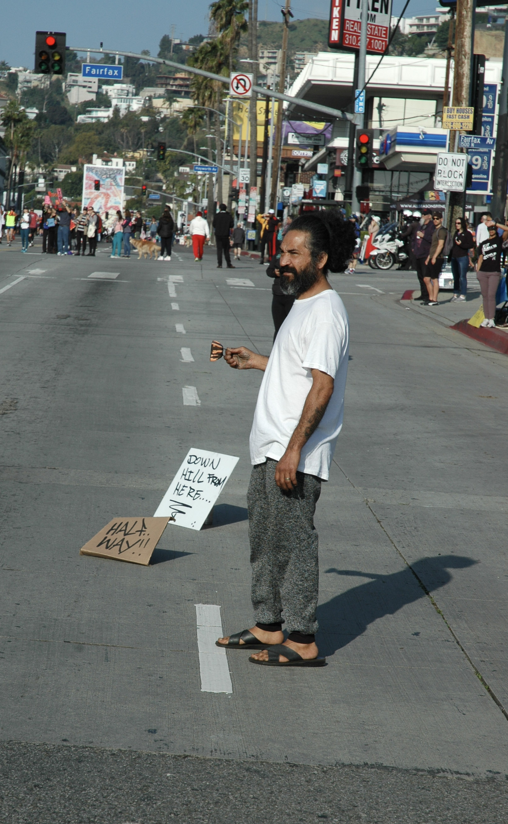 A Los Angeles Marathon spectator marks the "Half Way!!" point in the race, as he watches the marathon go by. The half-way point of the race, mile 13, was located at the intersection of Sunset Boulevard and Fairfax Avenue in Los Angeles, California on March 24, 2019. (Dakota Castets-Didier/The Corsair)