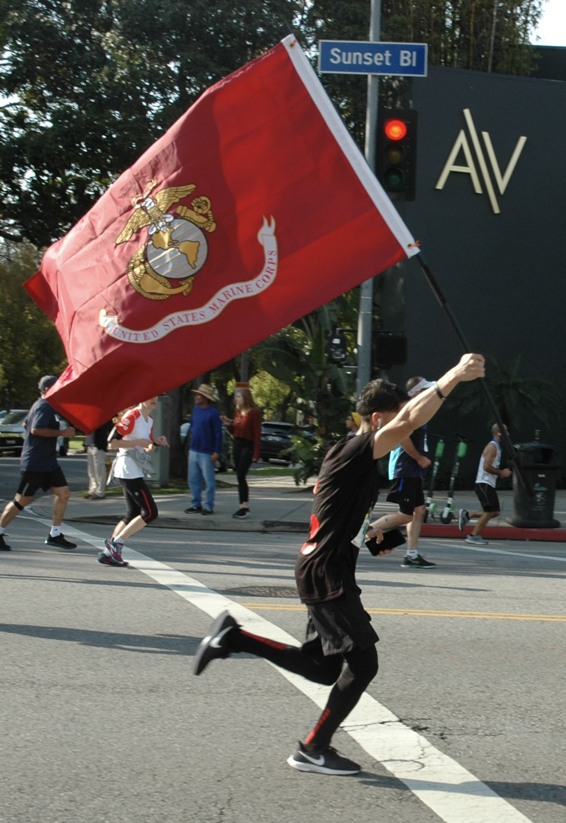  A runner participating in the Los Angeles Marathon waves a United States Marine Corps. flag as he approaches the half-way point of the race in Los Angeles, California, on March 24, 2019.  (Dakota Castets-Didier/The Corsair) 